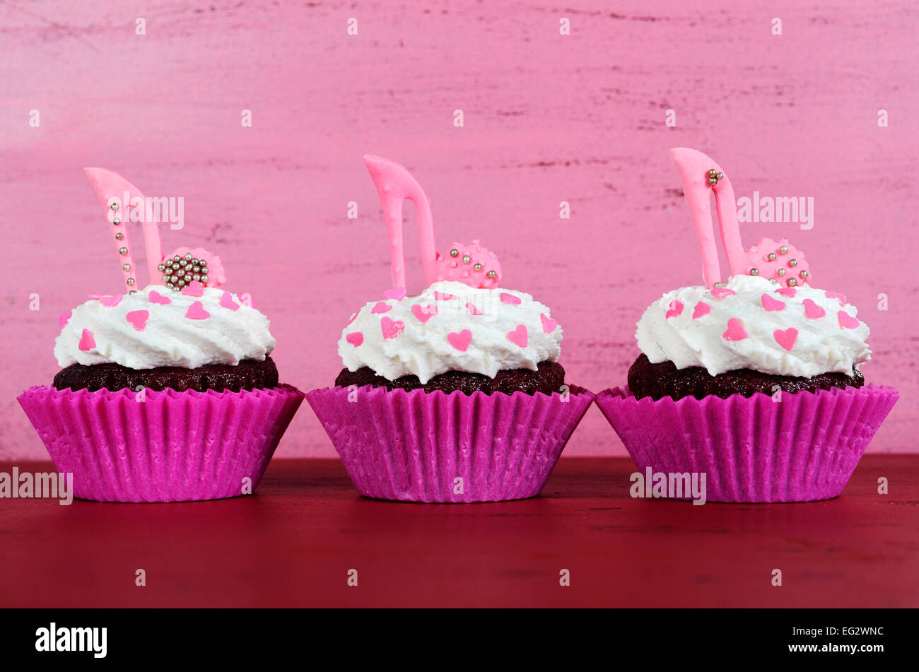 La Journée internationale des femmes, le 8 mars, cupcakes avec talon haut stiletto chaussures fondant sur fond de bois rose vintage. Banque D'Images