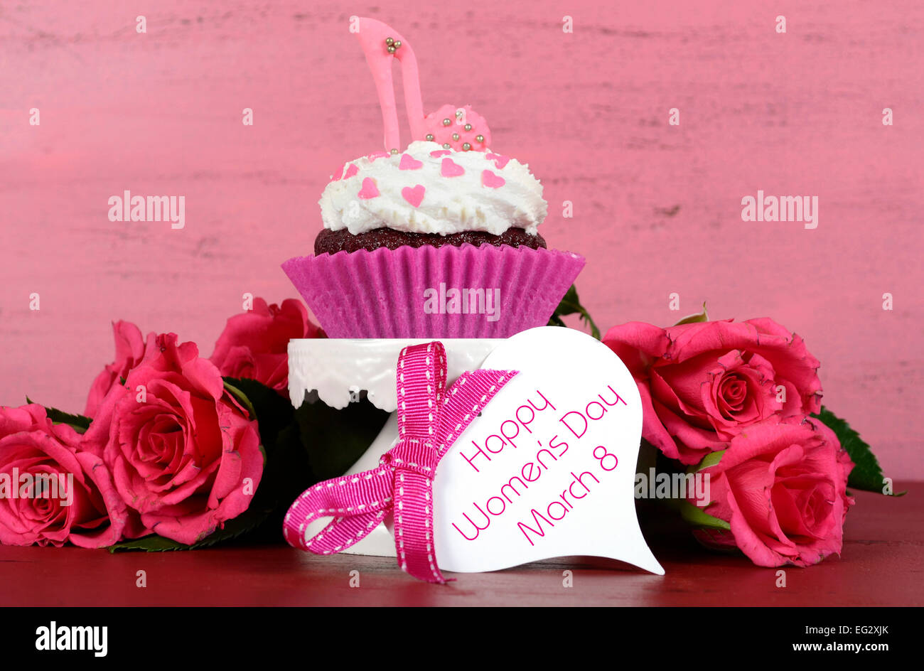 La Journée internationale des femmes, le 8 mars, cupcakes avec talon haut stiletto chaussures fondant sur fond de bois rose vintage. Banque D'Images