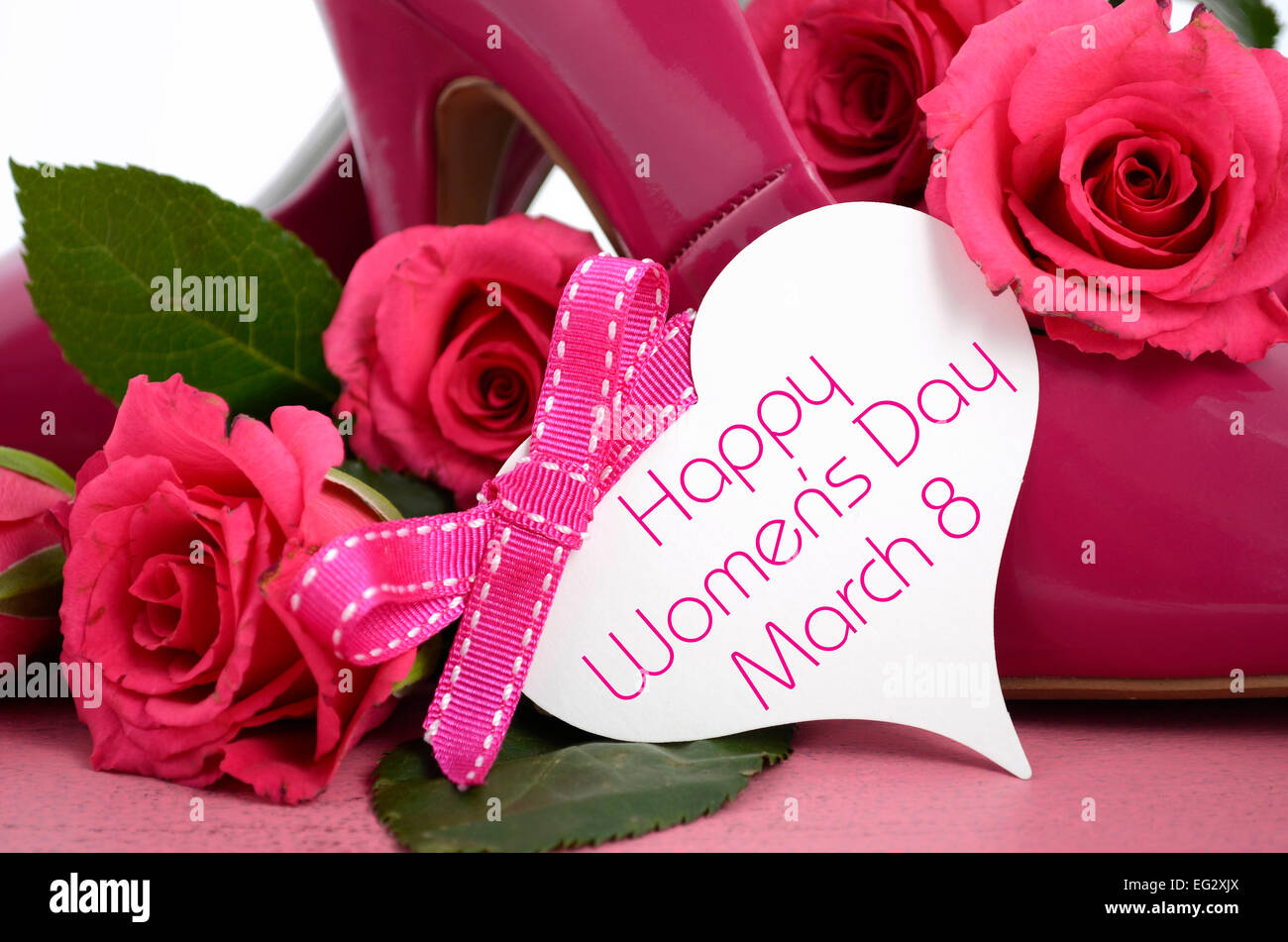 La Journée internationale des femmes, le 8 mars, dames rose talon haut stiletto chaussures et roses sur fond de bois rose vintage. Banque D'Images