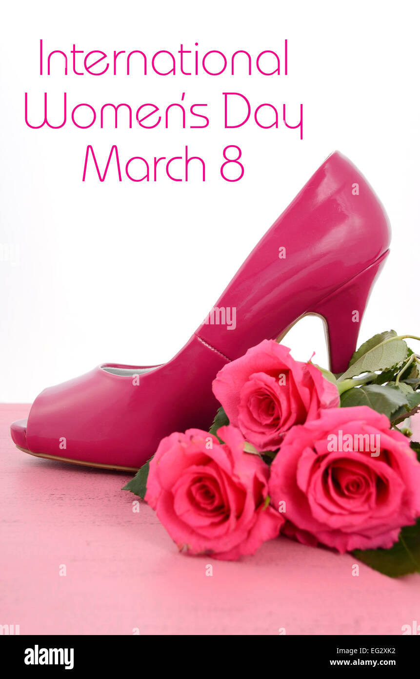 La Journée internationale des femmes, le 8 mars, dames rose talon haut stiletto chaussures et roses sur fond de bois rose vintage Banque D'Images