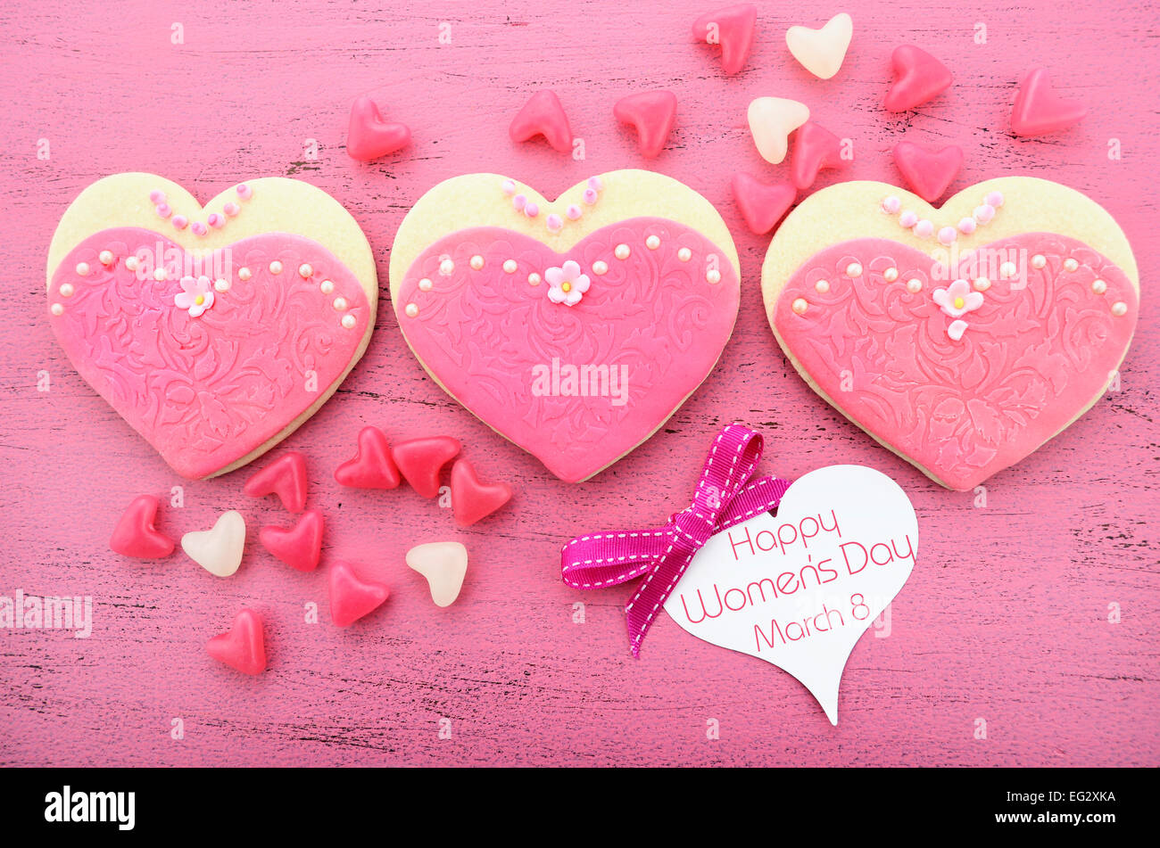 La Journée internationale des femmes, le 8 mars, les cookies en forme de coeur décorée en rose robes femmes rose vintage sur fond de bois. Banque D'Images