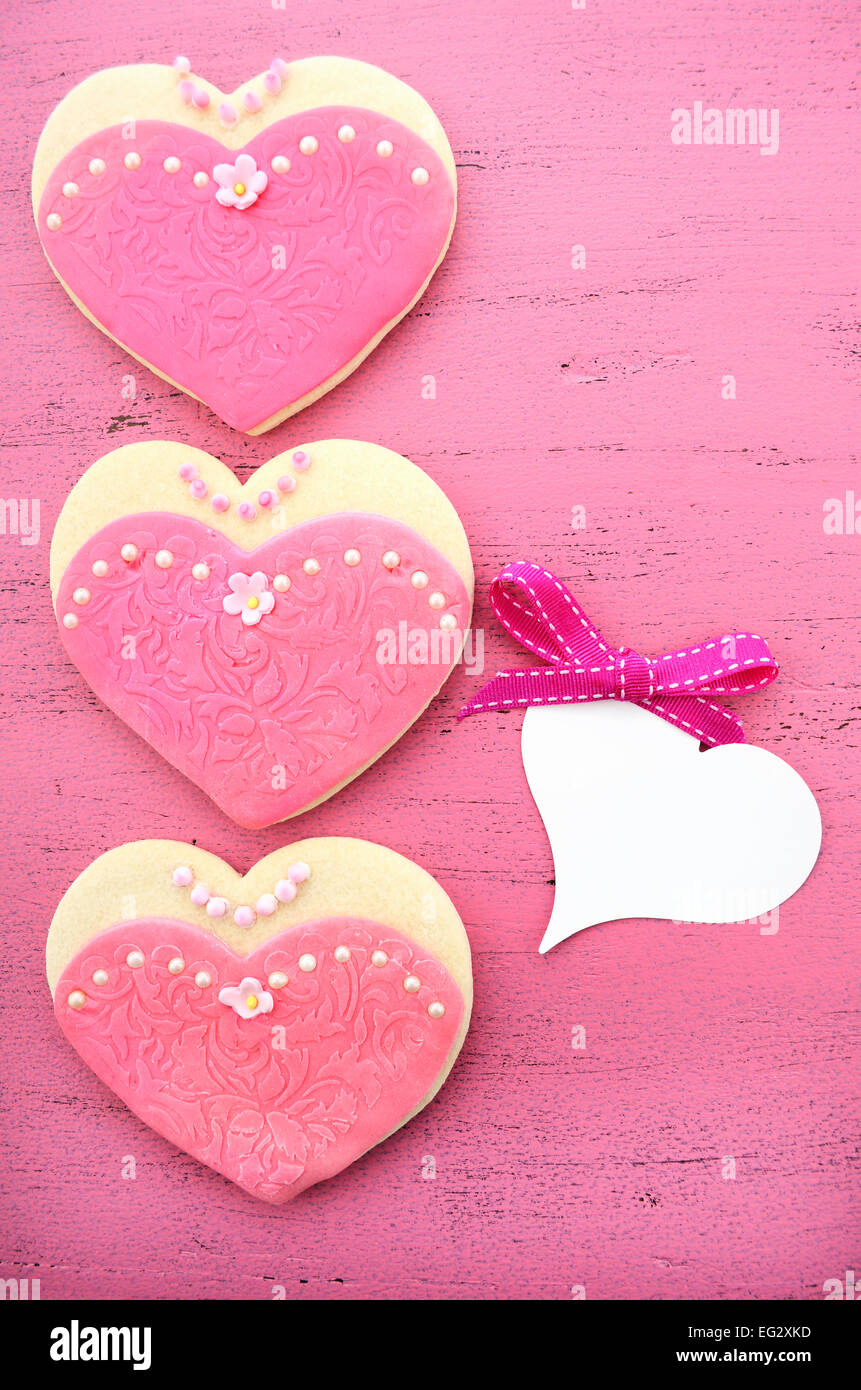 Les cookies en forme de coeur décorée en rose robes de dames sur fond de bois rose vintage Banque D'Images