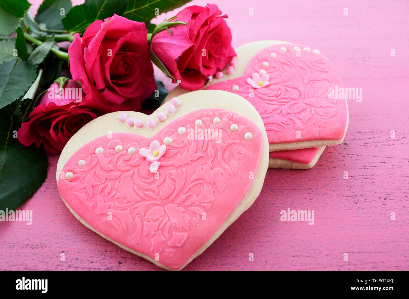 Les cookies en forme de coeur décorée en rose chers robes avec bouquet de roses roses Banque D'Images