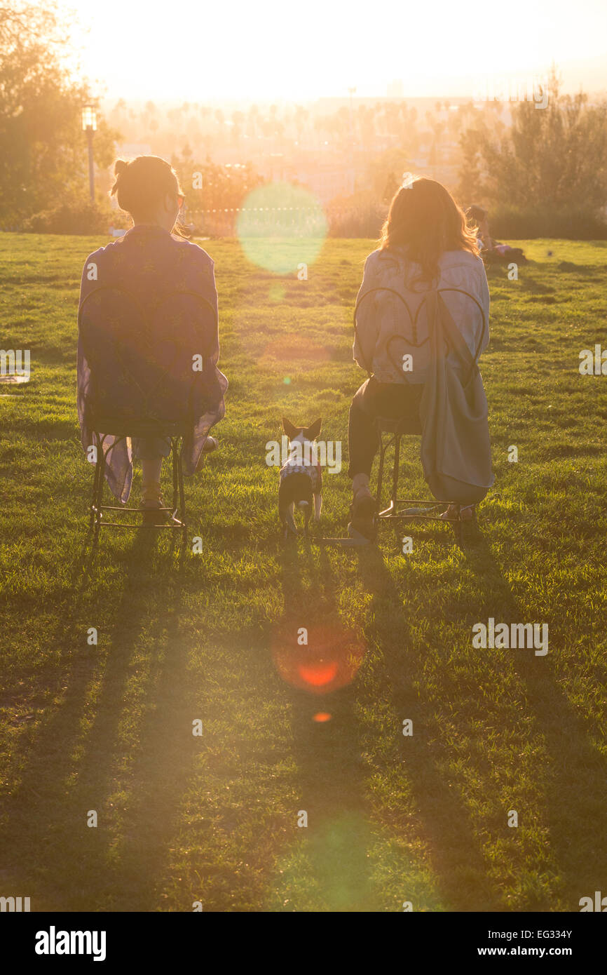 Deux femmes assises sur des chaises et un chien en regardant le coucher du soleil d'Olive Hill dans l'Est de Hollywood, CA Banque D'Images