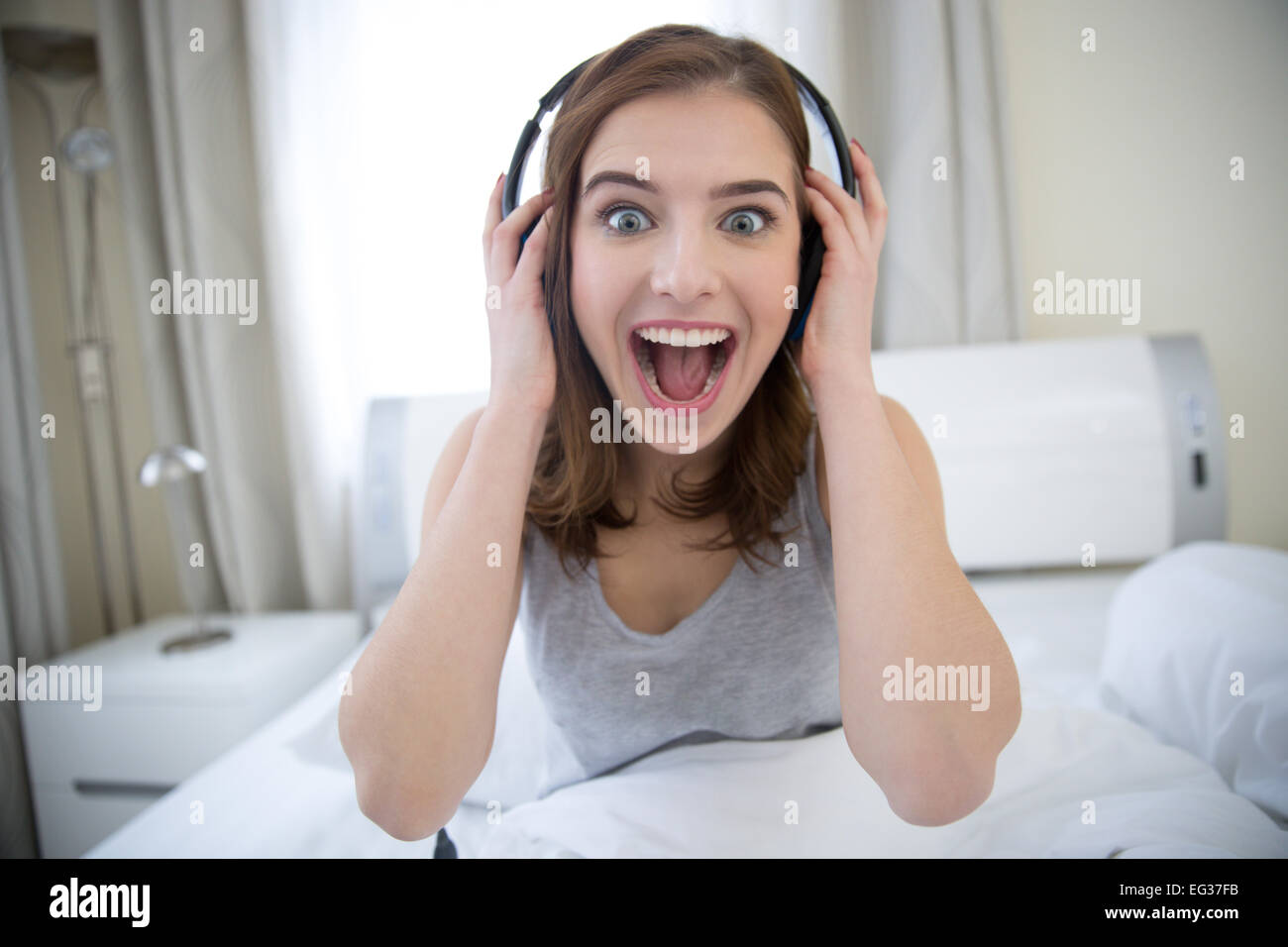 Surpris jeune femme avec un casque à la maison Banque D'Images