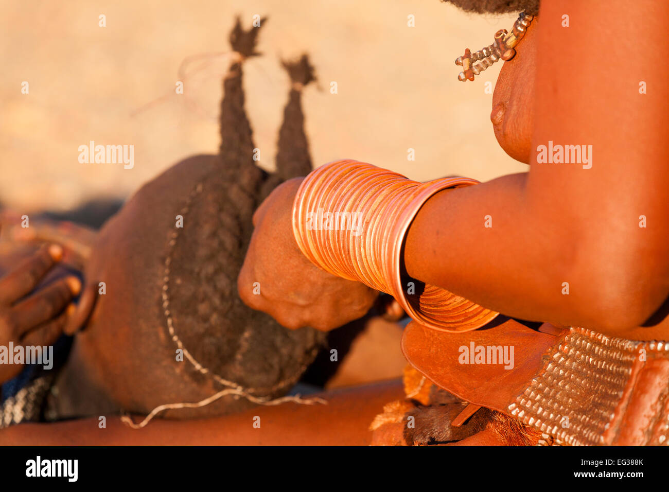 Une femme Himba tresses traditionnel sur une jeune fille, la Namibie. Banque D'Images