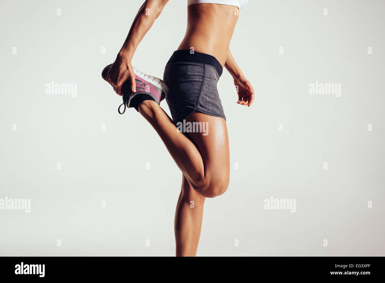 Portrait d'une femme de remise en forme s'étendant ses jambes contre fond gris. Monter coureuse faisant s'étend. Banque D'Images
