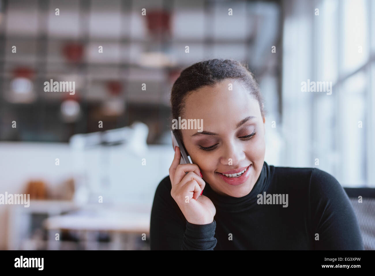 Libre de droit de jeune femme parlant au téléphone mobile. African American female model using cell phone au travail. Banque D'Images