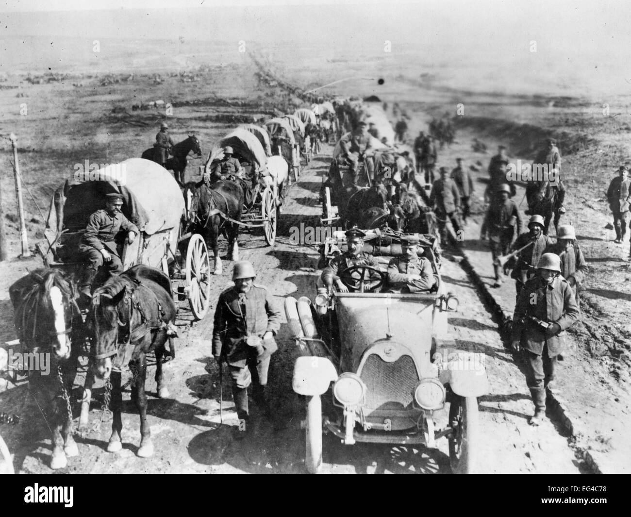 Les officiers allemands dans une voiture sur la route avec un convoi de wagons ; les soldats à pied le long de la route. La Première Guerre mondiale Banque D'Images