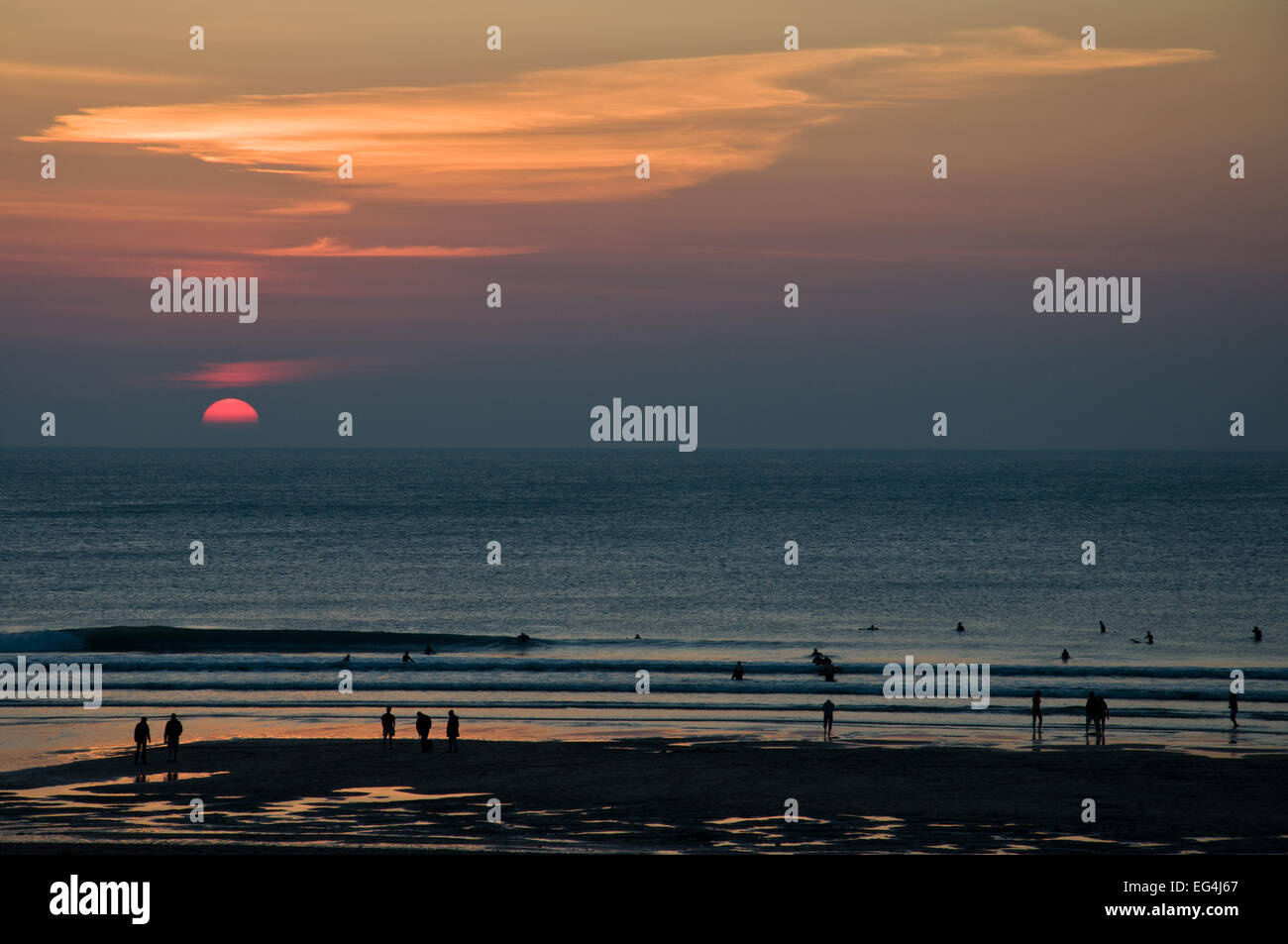 Les surfeurs sur la plage au coucher du soleil, le Watergate Bay, Cornwall, Angleterre Banque D'Images