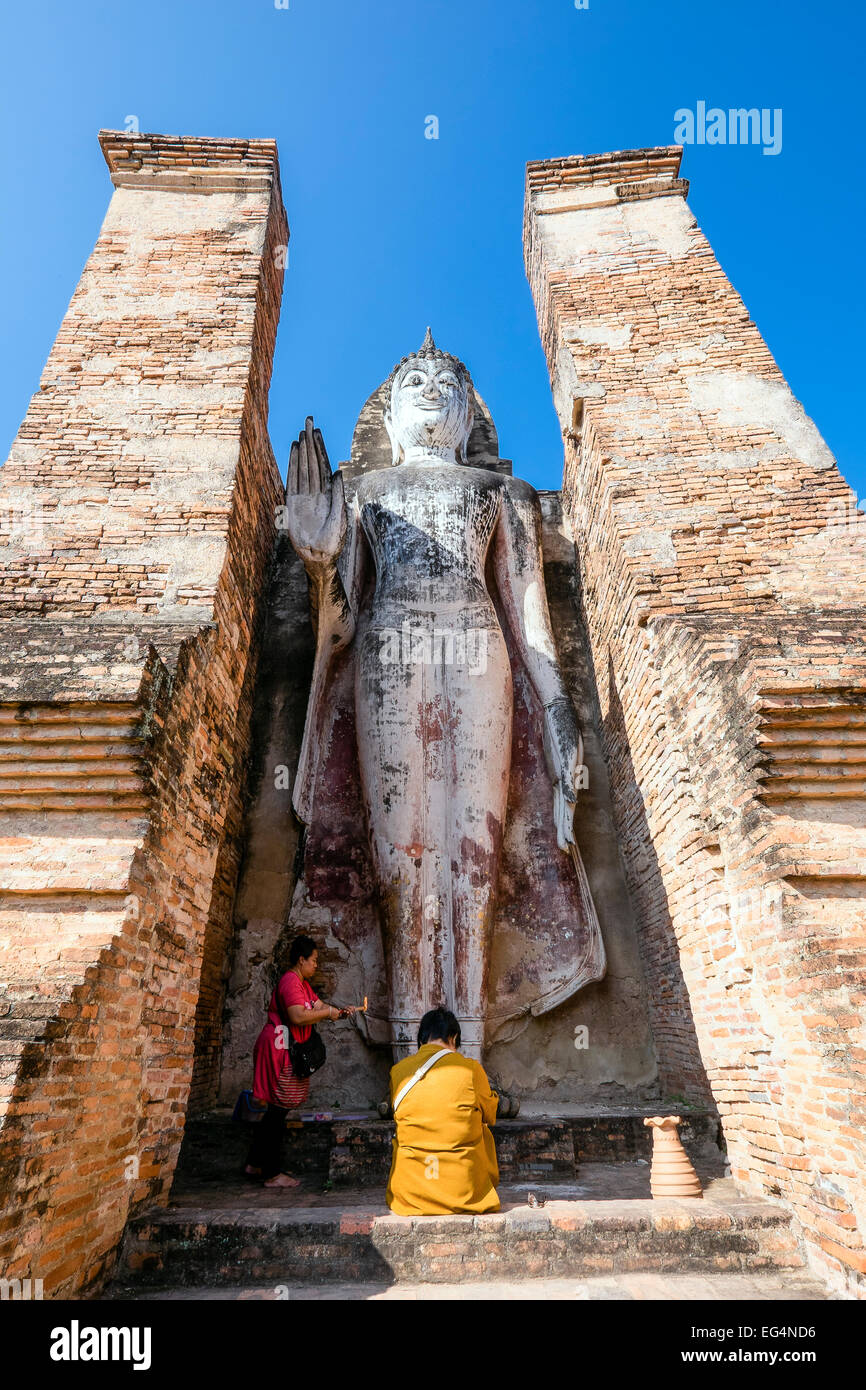 L'Asie. La Thaïlande, l'ancienne capitale du Siam. Parc archéologique de Sukhothai. Wat Mahathat Femmes donnant offrandes au Bouddha. Banque D'Images