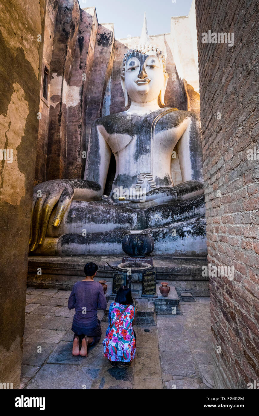 L'Asie. La Thaïlande, l'ancienne capitale du Siam. Parc archéologique de Sukhothai, le Wat Si Chum. Couple à genoux priant devant Bouddha. Banque D'Images