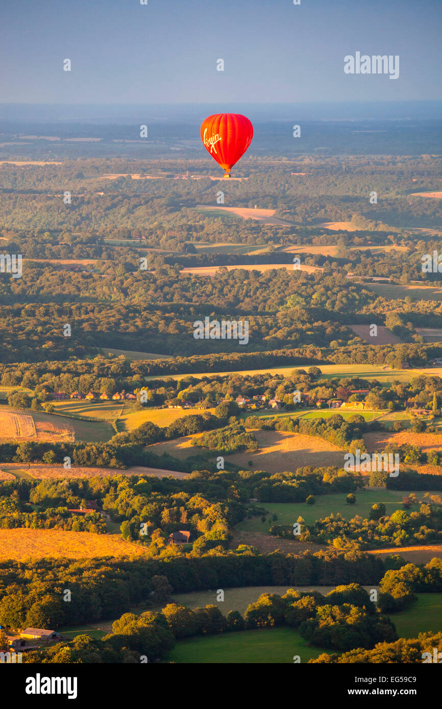 Red hot air balloon flying over rural landscape, south Oxfordshire, Angleterre Banque D'Images