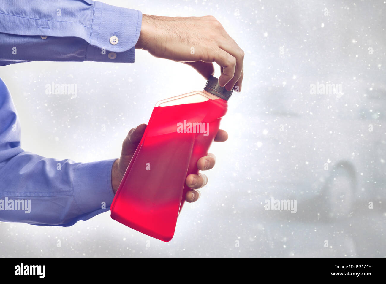 Homme avec une bouteille d'additif antigel liquide à base d'eau pour l'hiver l'état de conduire. La tonalité de l'image. Banque D'Images