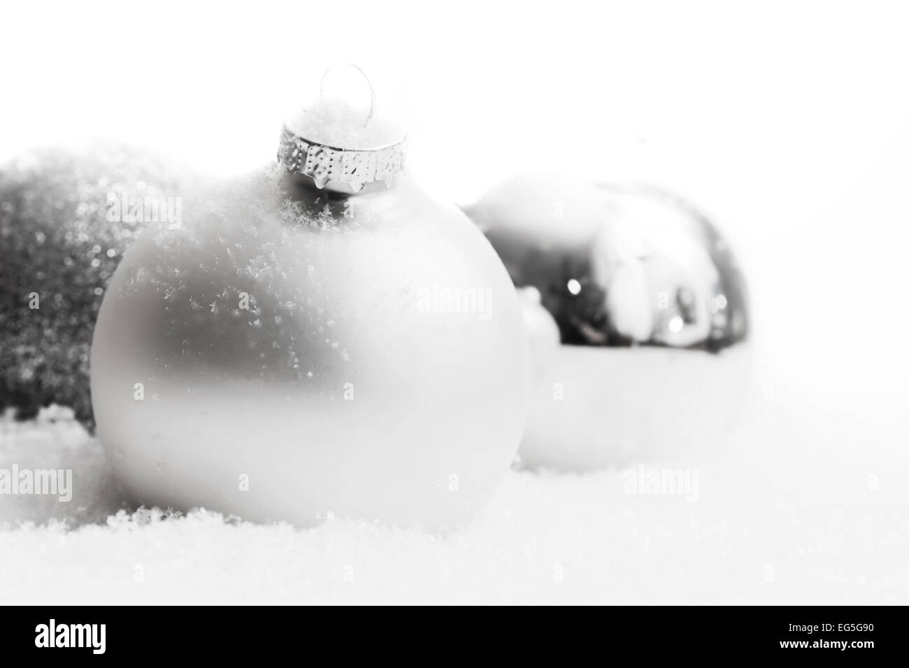 Boules de Noël en verre blanc sur la neige, l'hiver, le gel, l'arrière-plan feux scintillants. Banque D'Images