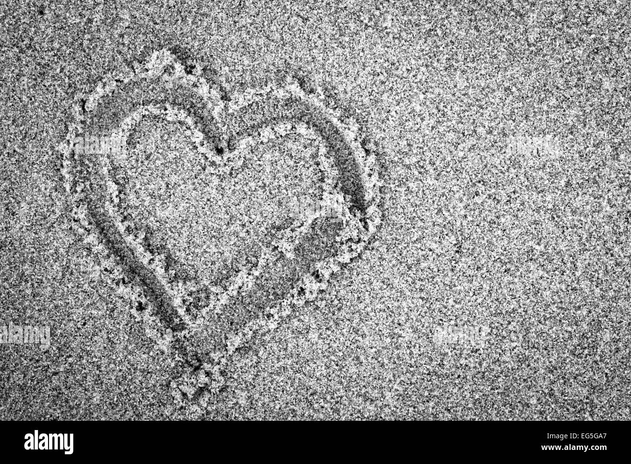 Forme de coeur sur le sable. Romantique, noir et blanc, à la main. Banque D'Images