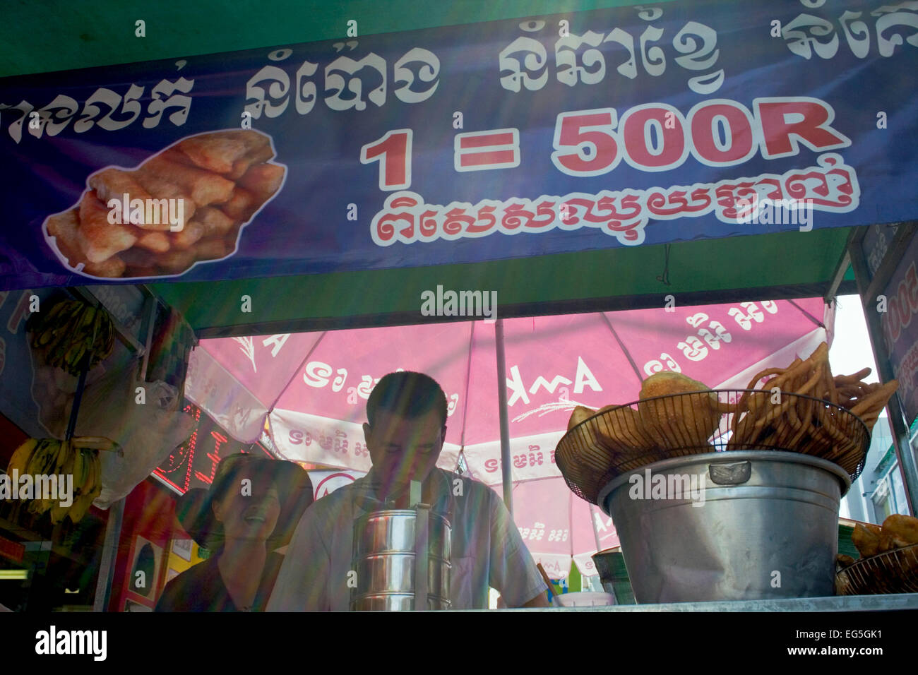 Un homme et femme sont différents de cuisson du pain dans l'huile chaude et le servir comme l'alimentation de rue sur une rue de ville de Phnom Penh, Cambodge. Banque D'Images