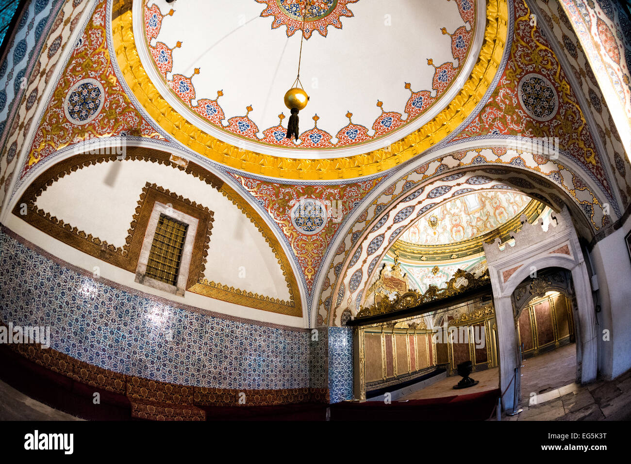Palais de Topkapi salle du conseil impérial intérieur Istanbul // ISTANBUL, Turquie — L'intérieur de la salle du conseil impérial du palais de Topkapi présente la salle ornée où les fonctionnaires de l'État ottoman menaient les affaires du gouvernement. Le Conseil impérial, connu sous le nom de Dîvân-ı Hümâyûn, sert de lieu de rencontre pour le Grand vizir, les vizirs et d'autres hauts fonctionnaires de l'Empire ottoman. La fenêtre dorée de la salle est reliée à la Tour de Justice, renforçant ainsi l'importance symbolique de la justice dans la gouvernance ottomane. Le palais de Topkapi a fonctionné comme résidence principale et siège administratif Banque D'Images