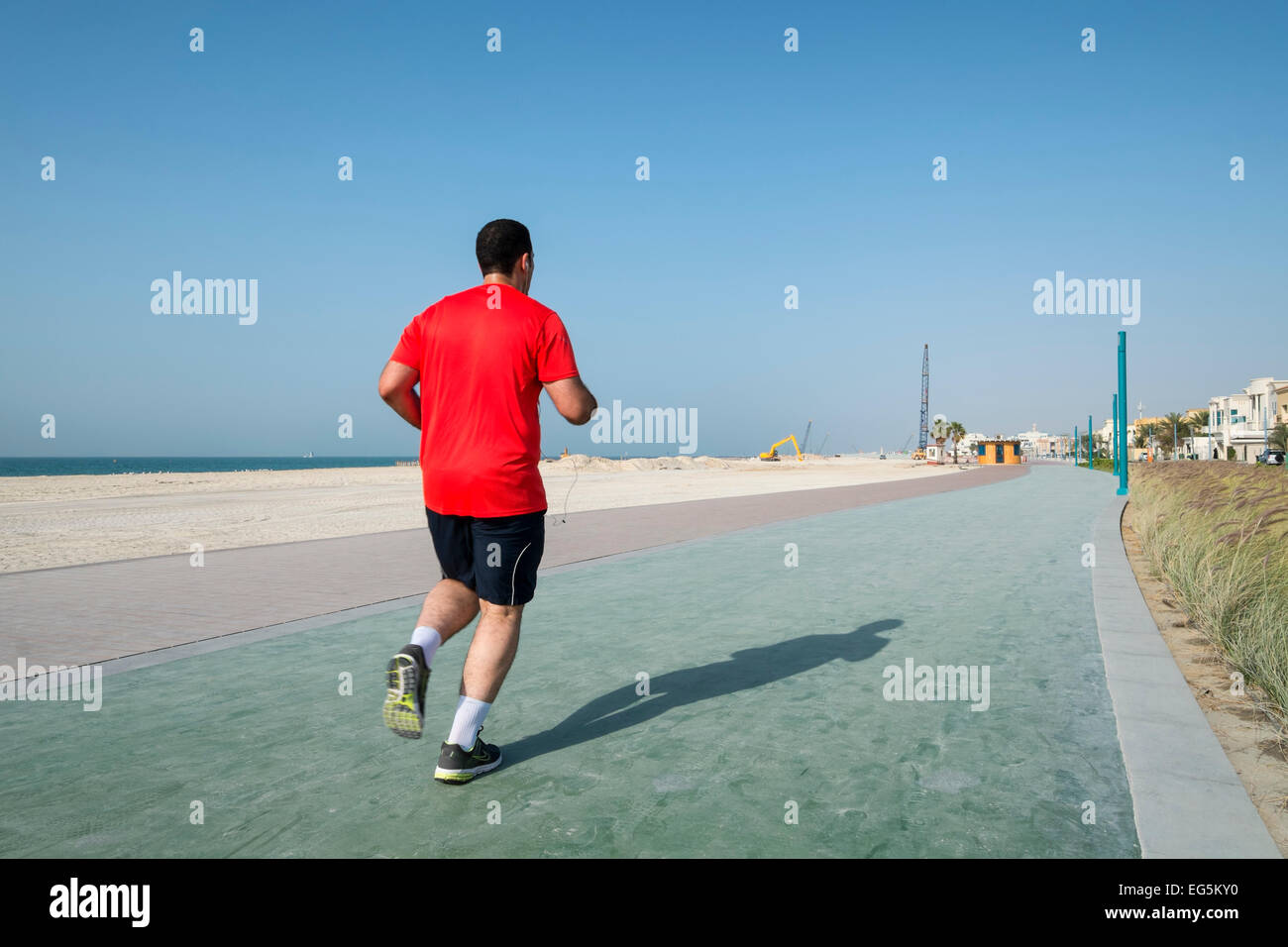 Man jogging on nouvelle piste de marche et de jogging réaménagés le long beach à Umm Suqueim à Dubaï Émirats Arabes Unis Banque D'Images