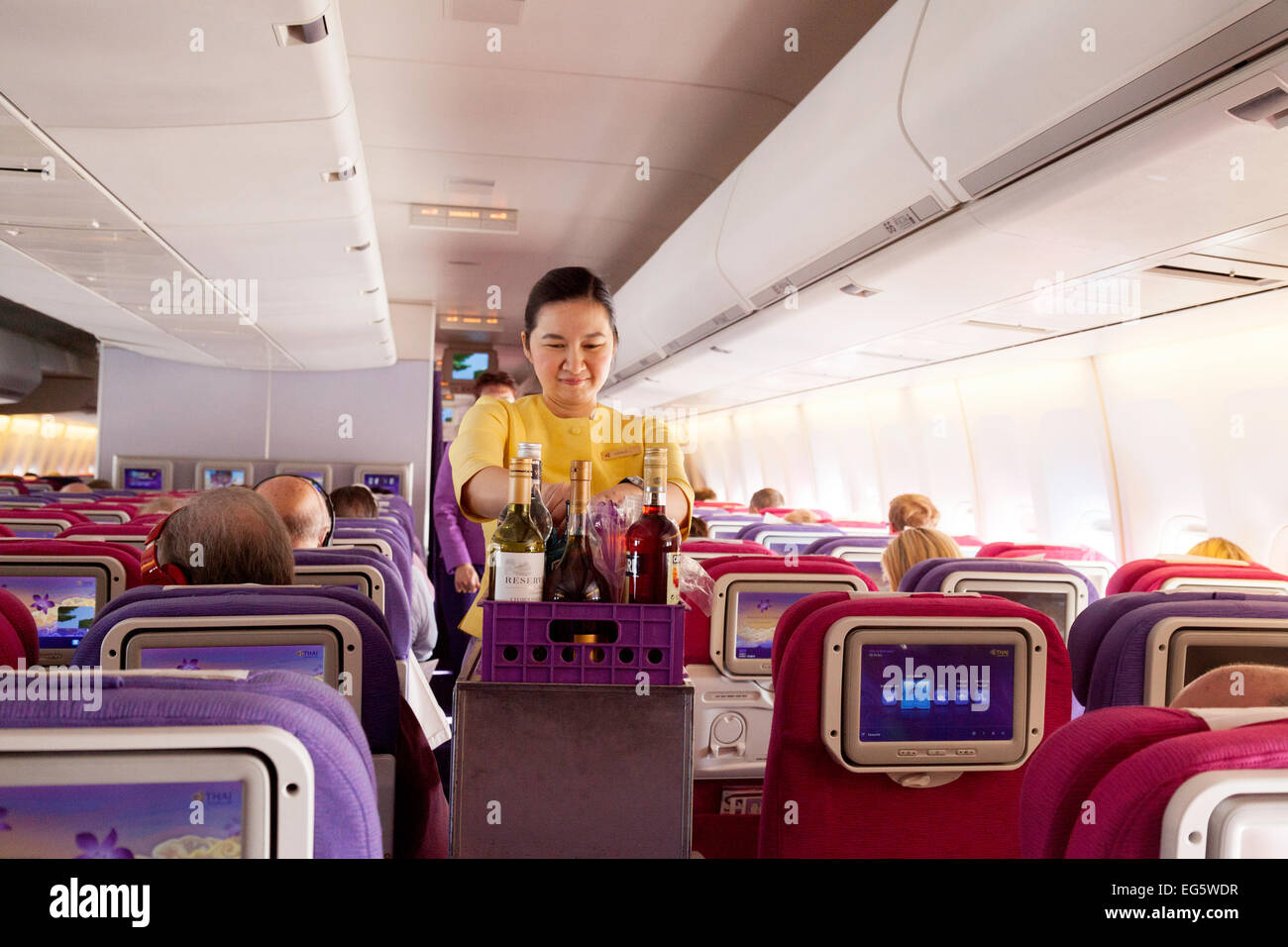 Une hôtesse de l'air, servant des boissons sur un vol de Thai Airways International de Londres à Bangkok Banque D'Images