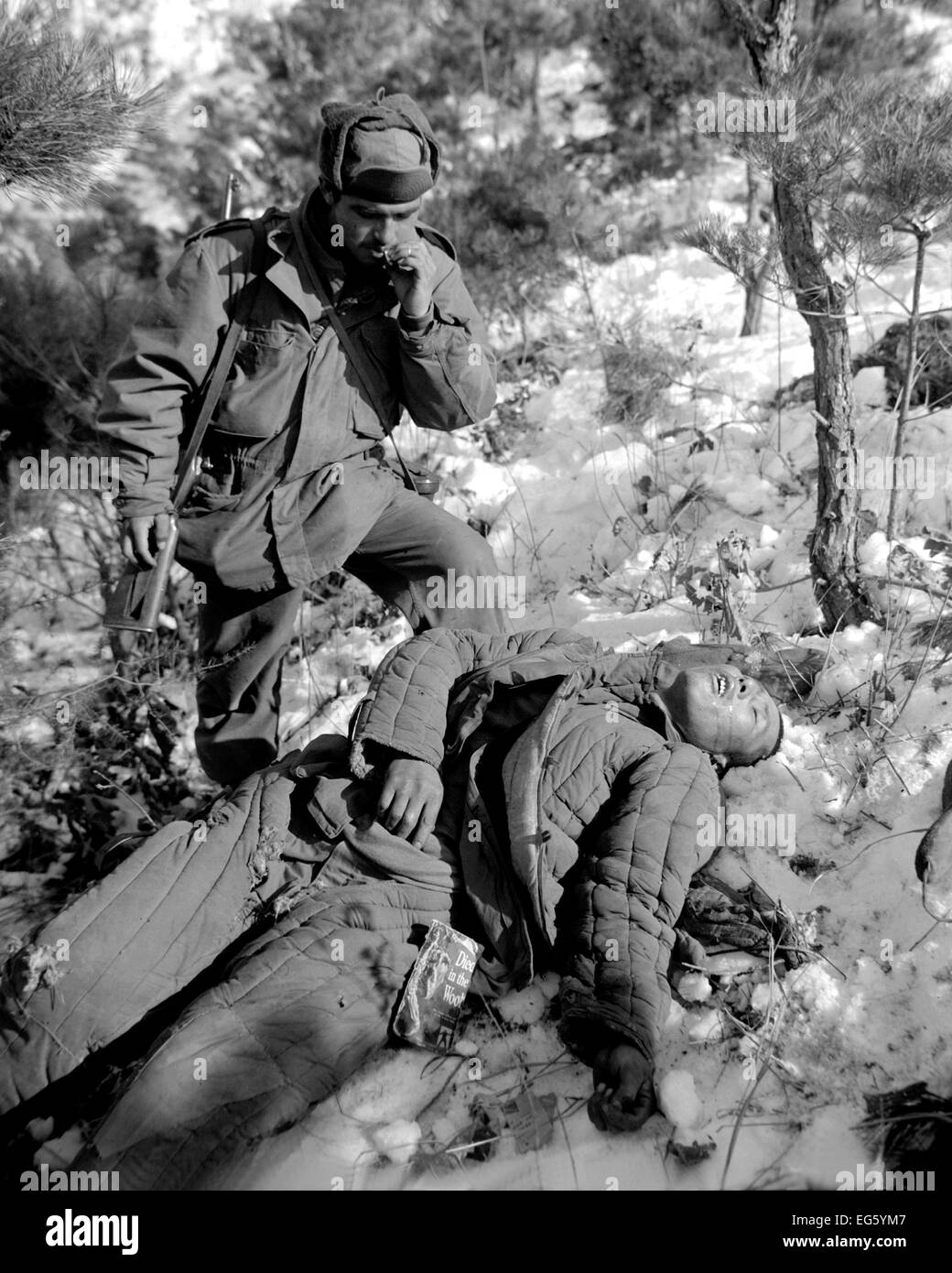 Guerre de Corée :(1950-1953) Le sergent américain. Mike Chalooga examine un communiste chinois morts tués pendant l'offensive de route près de la rivière Han, Corée. Le soldat porte GI vêtements et de transporter un American Short story magazine. Photo:US Army Banque D'Images