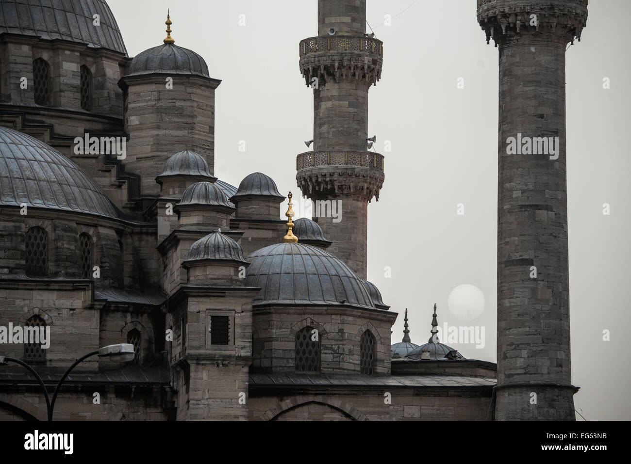 ISTANBUL, Turquie / Türkiye — le soleil couchant s'abaisse derrière une épaisse brume entre les minarets de la nouvelle Mosquée d'Istanbul. Banque D'Images