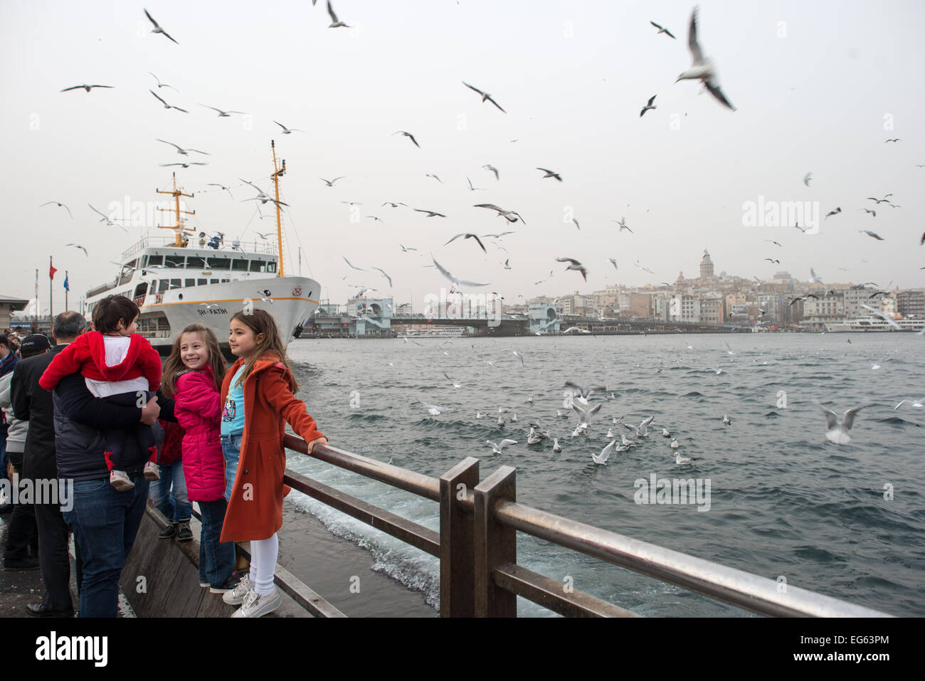 ISTANBUL, Turquie / Türkiye — deux petites filles posent pour des photos avec les mouettes sur le front de mer d'Eminonu à Istanbul. En arrière-plan se trouve la Tour de Galata. Banque D'Images