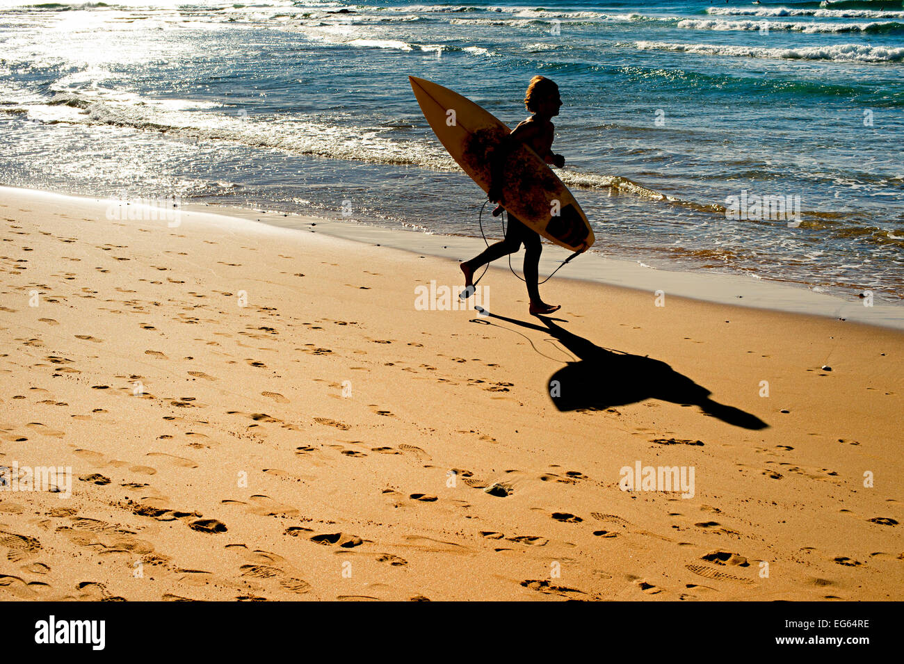 Jeune homme qui court sur la plage vers l'océan. Portugal Banque D'Images