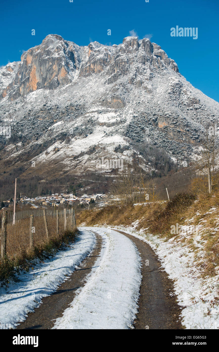 Piste enneigée avec marques de pneu menant vers la montagne couverte de neige, Sinsat, Ariège, Pyrénées, France Banque D'Images