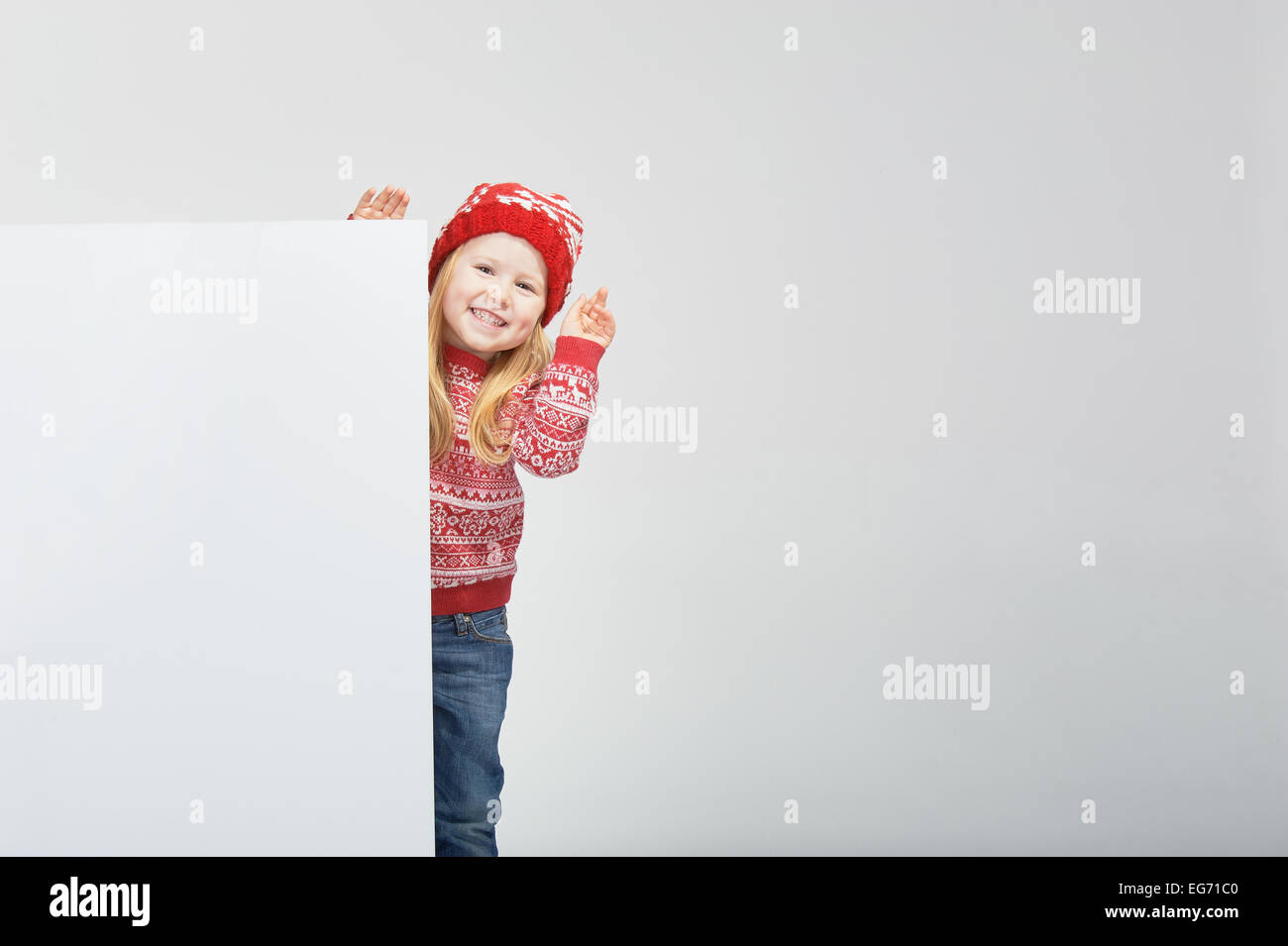 Smiling belle fille blonde dans un chapeau d'hiver rouge et blanc avec l'emplacement pour un texte ou une publicité Banque D'Images