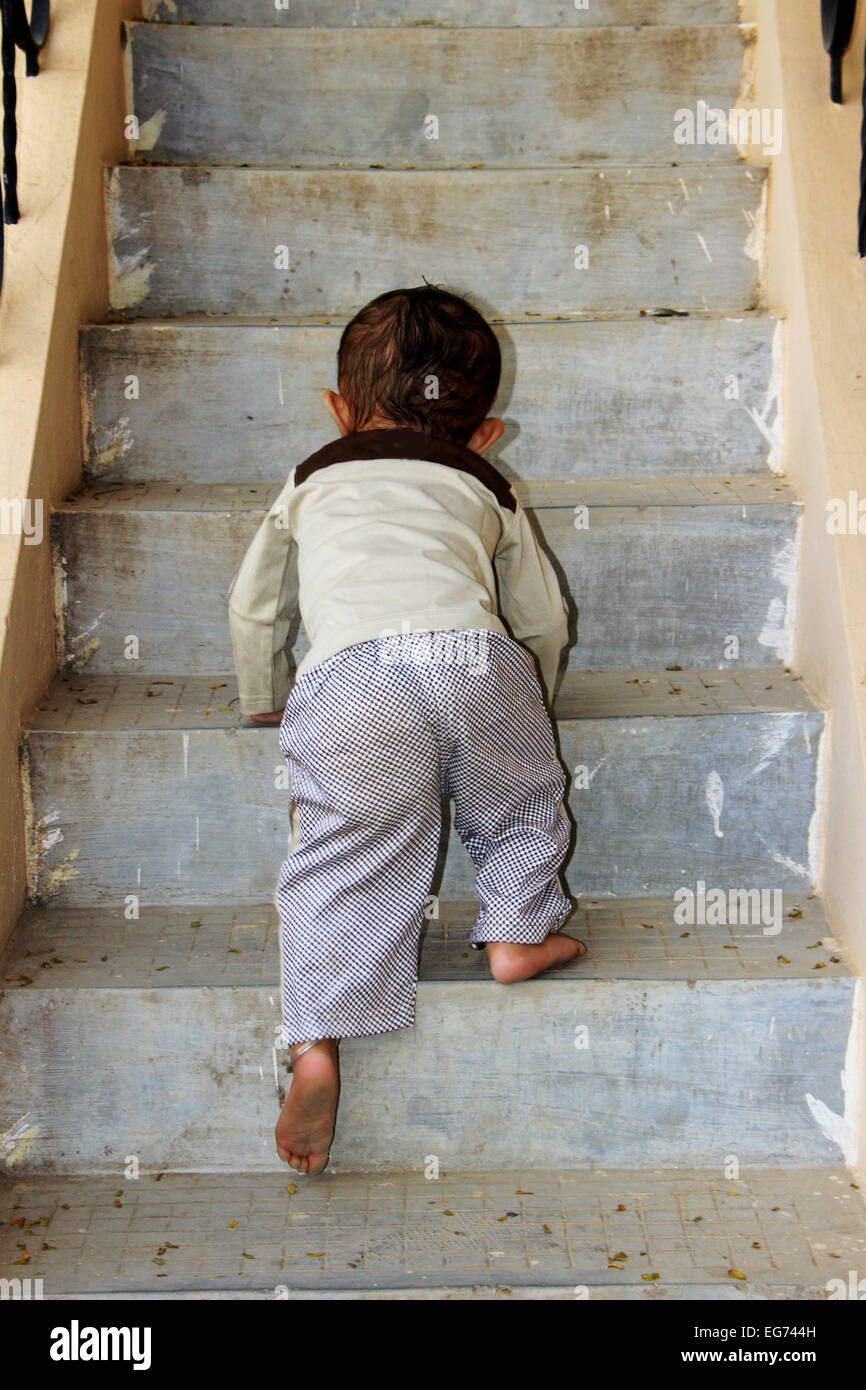 Jeune bébé garçon tenter de gravir les étapes d'escalier Banque D'Images