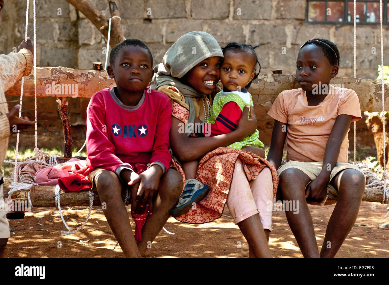 4 enfants s'asseoir sur le siège pivotant ensemble à Watoto Wa Baraka orphelinat, Kenya Banque D'Images