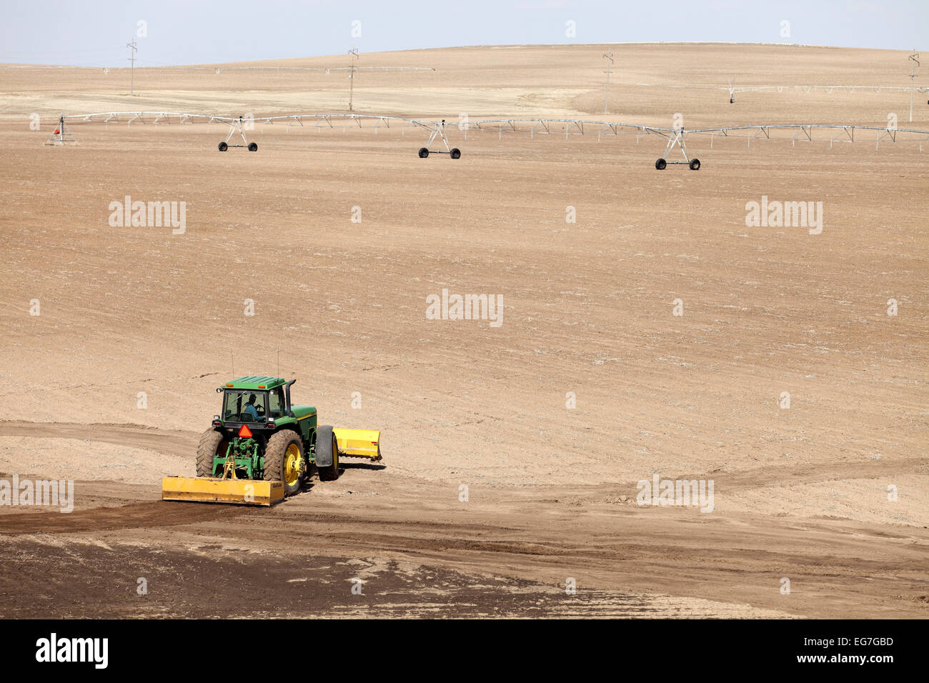 Un tracteur et un grattoir qui travaillent dans le domaine de la réparation des dommages de l'érosion. Banque D'Images