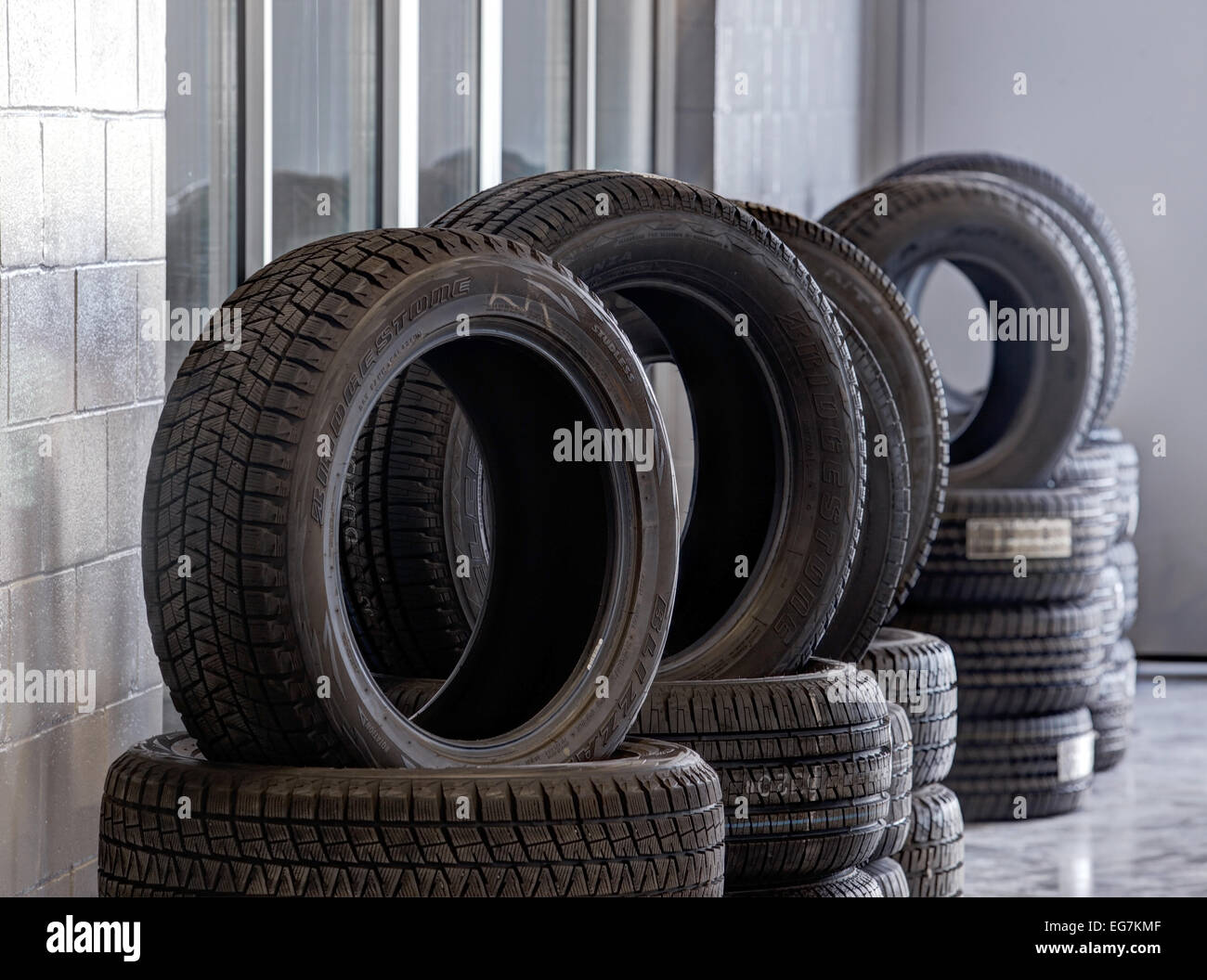 Des piles de pneus, avec bande de roulement pour diverses conditions de conduite, à vendre dans un garage de réparation automobile. Banque D'Images