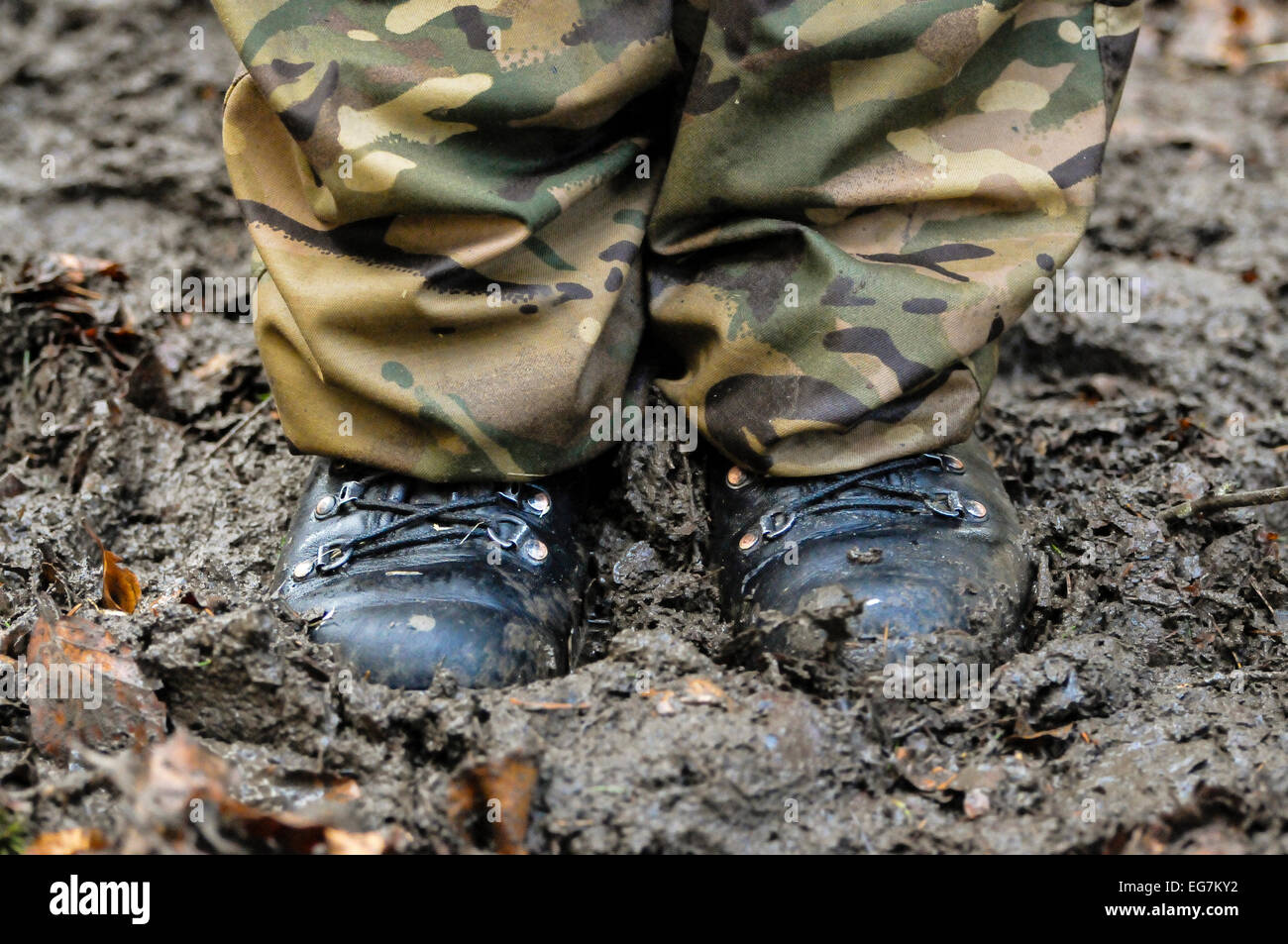 Un soldat porter des bottes et de camouflage se trouve dans la boue profonde Banque D'Images