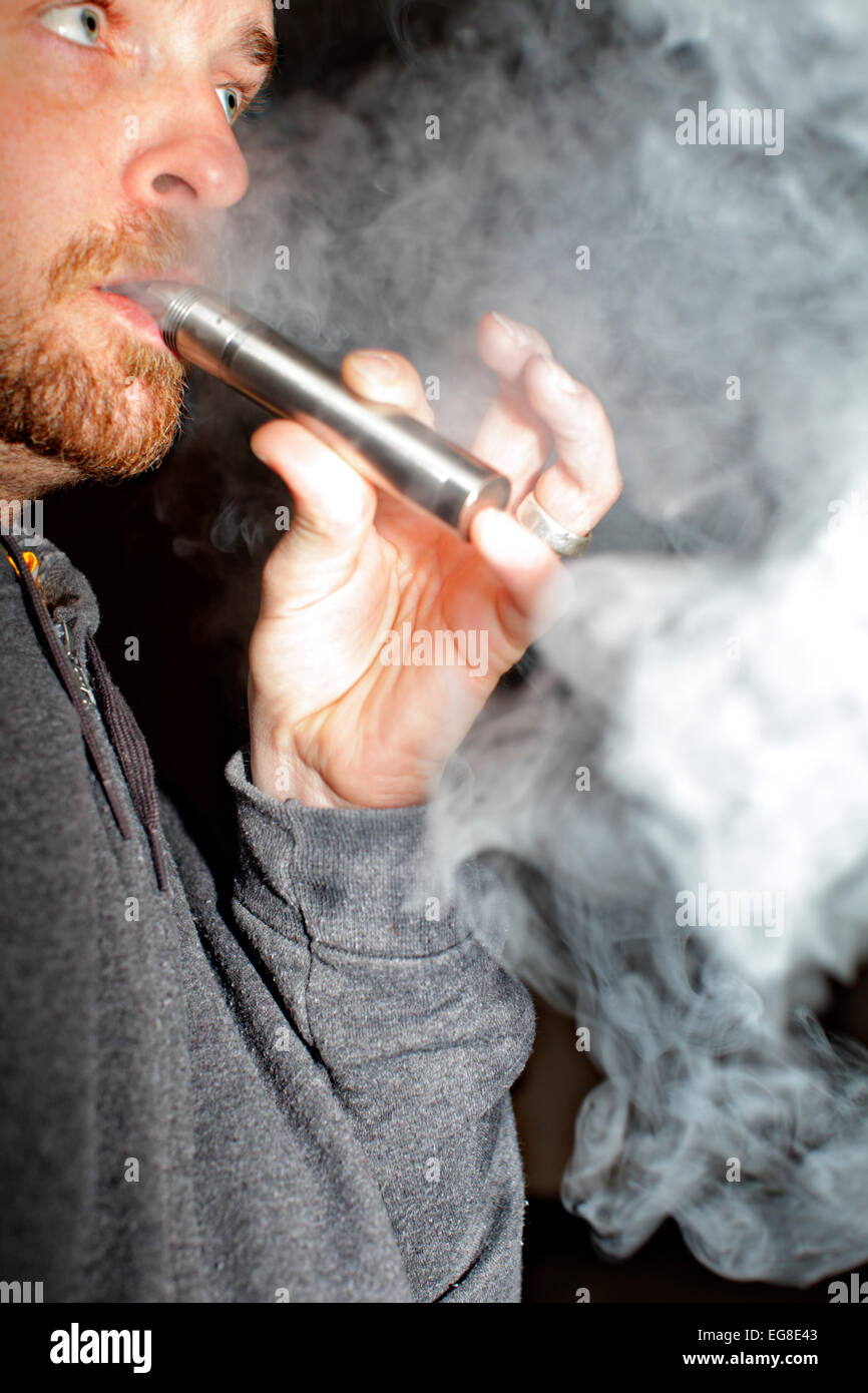 Un homme souffle de vapeur d'e-cigarette de son nez et la bouche Photo  Stock - Alamy