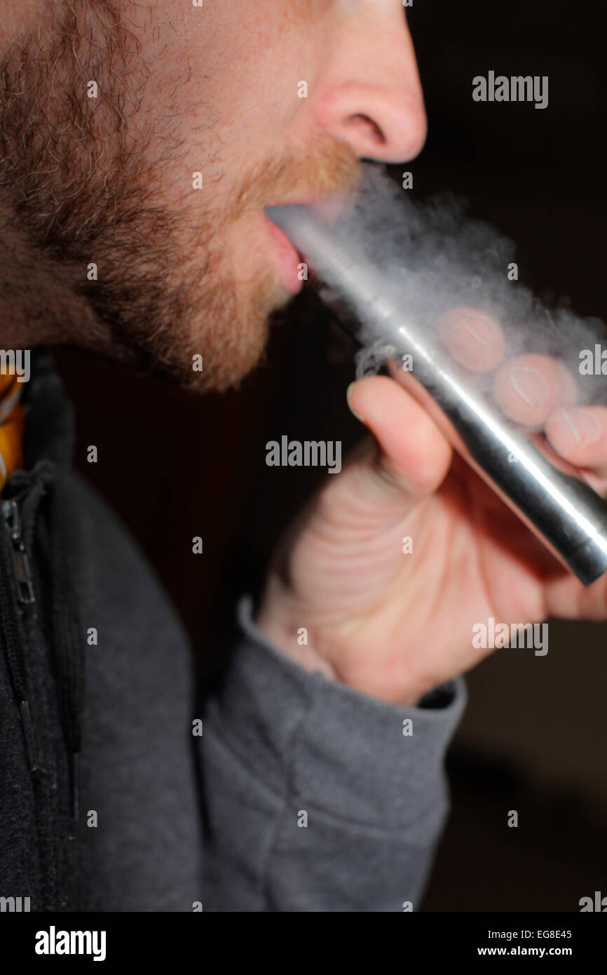 L'homme à l'aide d'une e-cigarette, soufflant de la vapeur. Banque D'Images