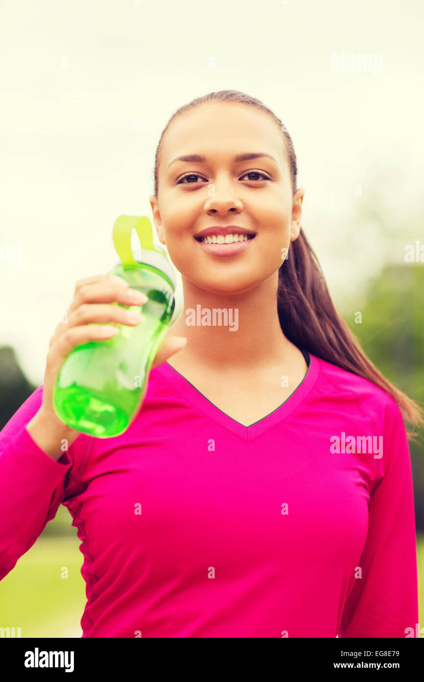 Smiling woman drinking from bottle Banque D'Images