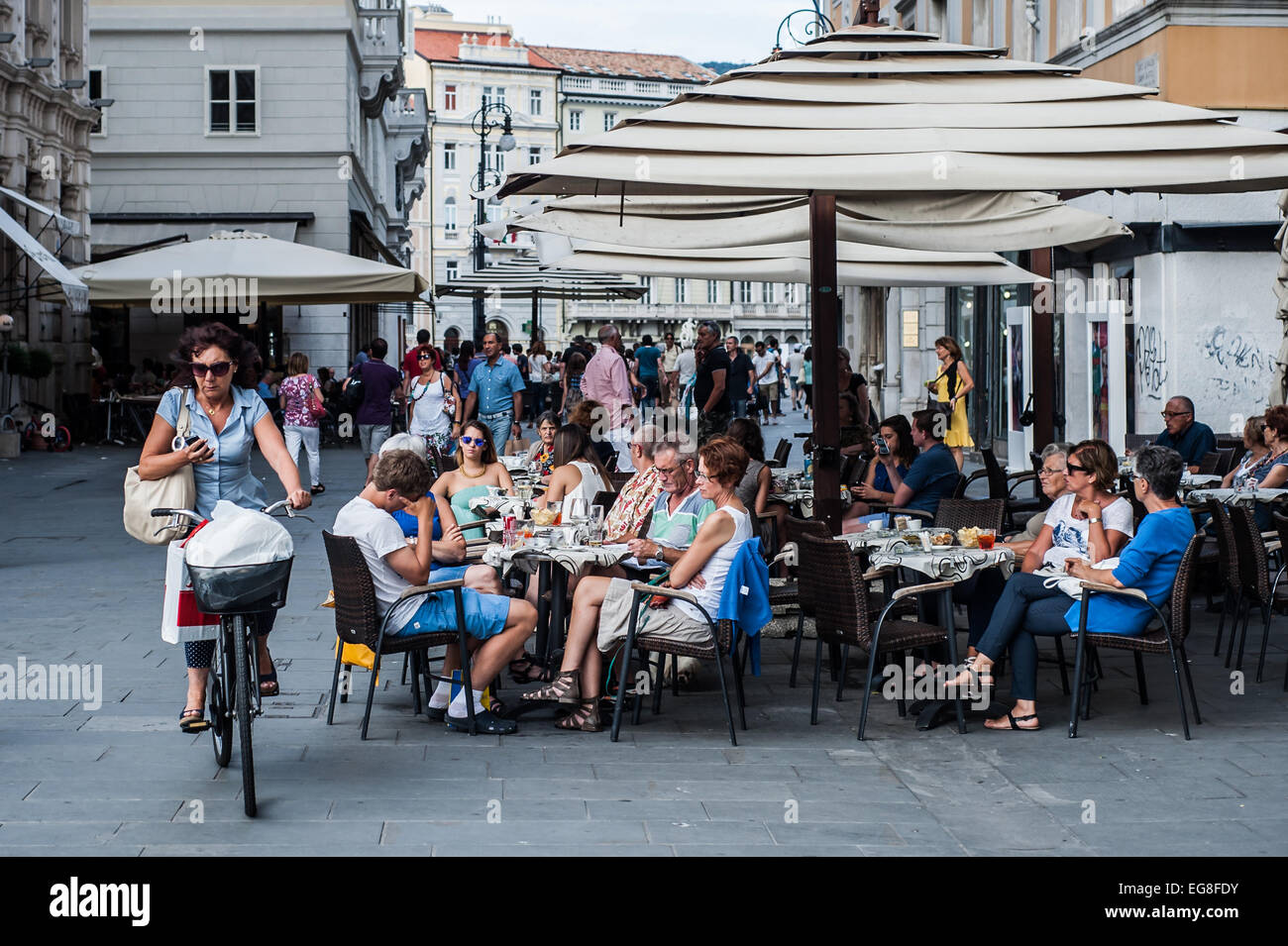 Trieste, Italie - Les gens aiment 'aperitivo' sur la place centrale Piazza dell'Unità d'Italia. Une femme rides son vélo. Banque D'Images