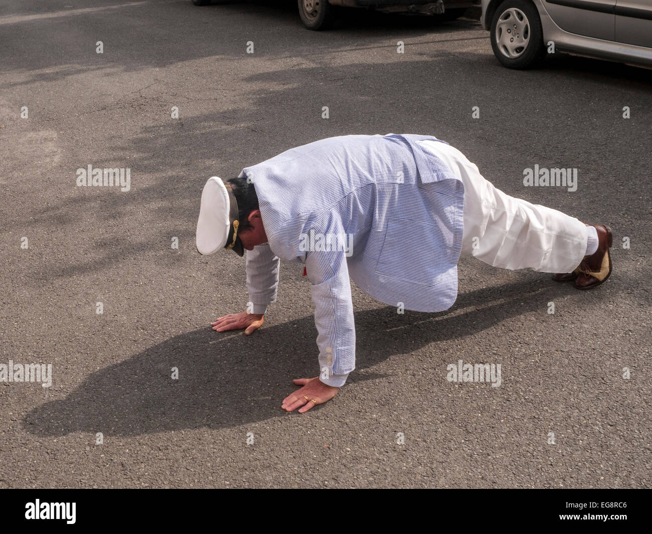 Bien-habillé man doing push-ups dans street - France. Banque D'Images