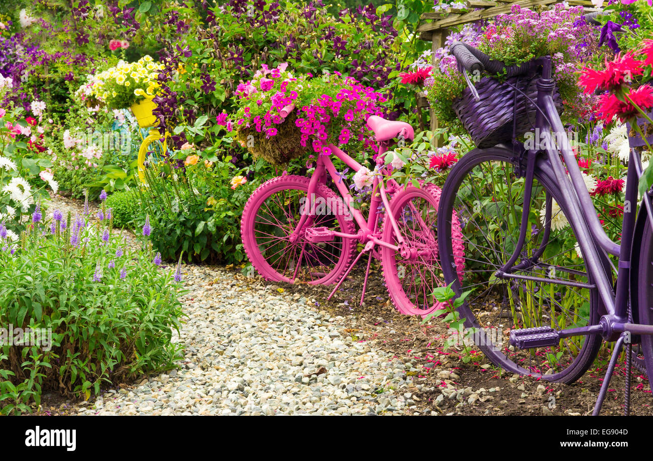 Jardin fantaisiste des bicyclettes, l'art des paniers remplis de fleurs qui déborde sur le jardin coloré au printemps. Banque D'Images Jardin fantaisiste des bicyclettes, l'art des paniers remplis de fleurs qui déborde sur le jardin coloré au printemps. Banque D'Images