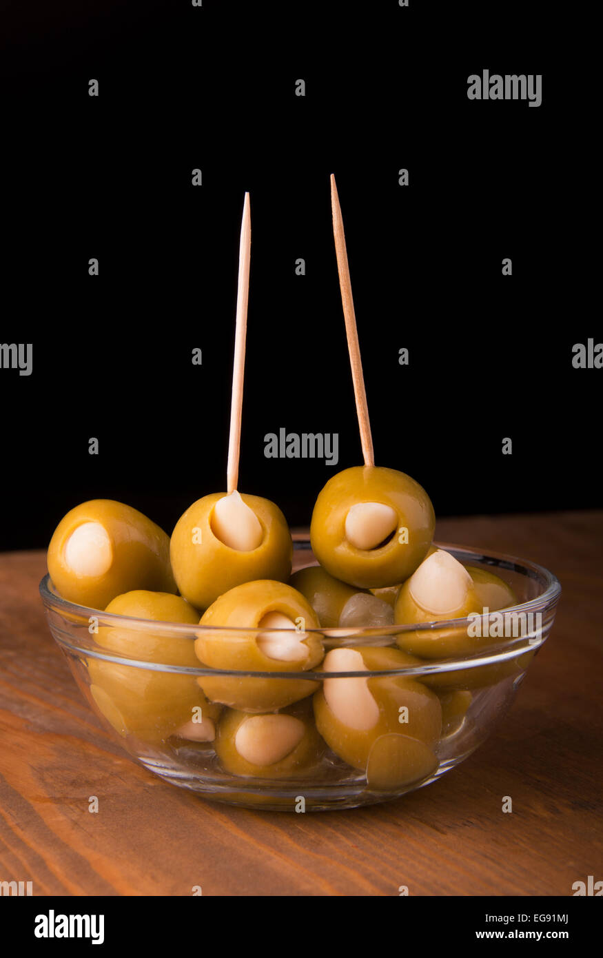 Green olives farcies à l'ail dans un bol en verre sur la table en bois, sur un fond sombre Banque D'Images
