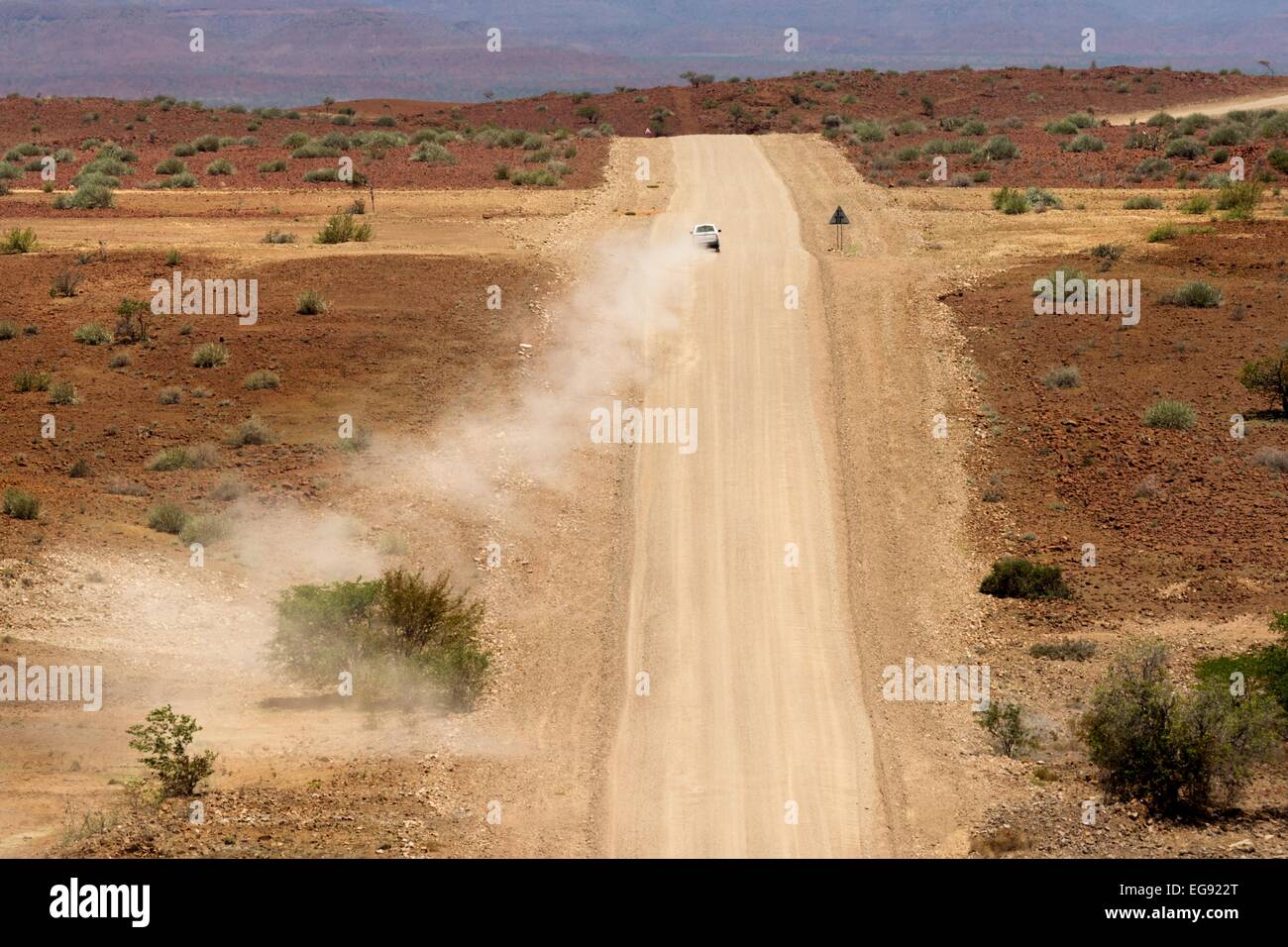 Un 4x4 blanc véhicule s'éloigne de la caméra sur une piste poussiéreuse à sec dans le nord de la Namibie, l'Afrique. Banque D'Images