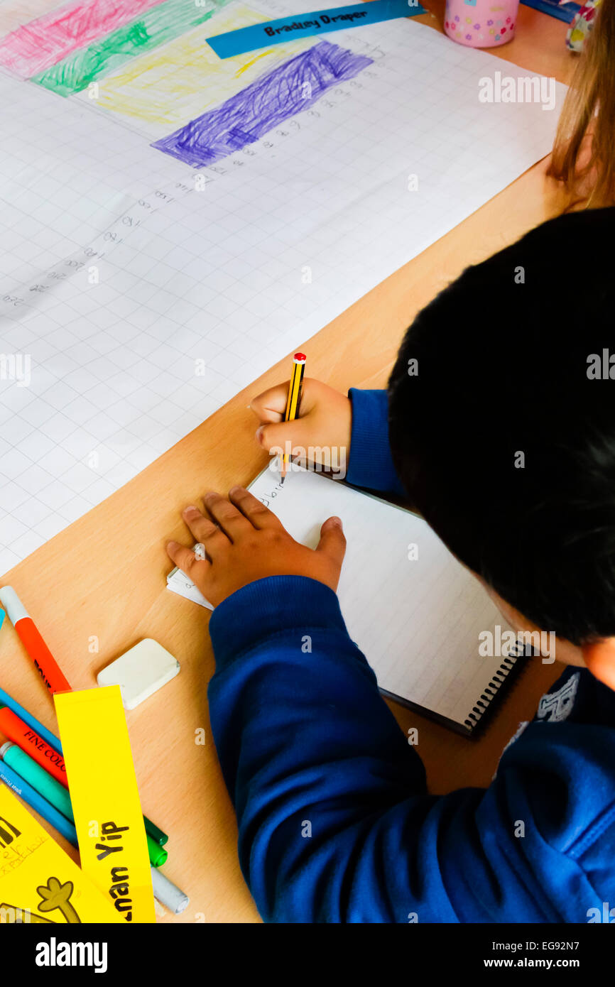 École primaire écrit avec un crayon pendant une leçon Banque D'Images