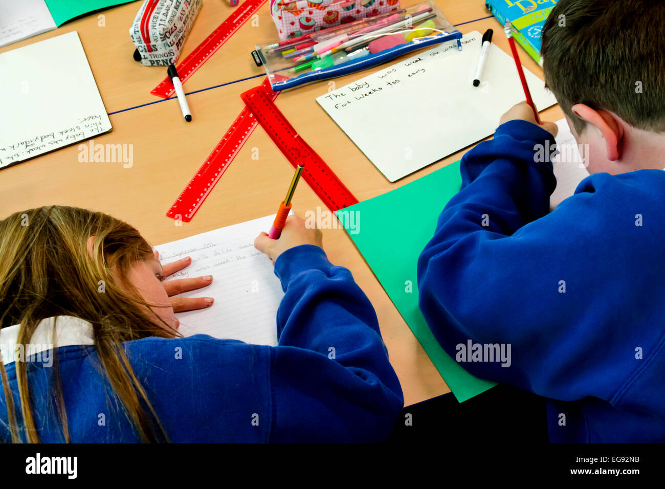 Les enfants de l'école primaire l'écriture avec un crayon pendant une leçon Banque D'Images