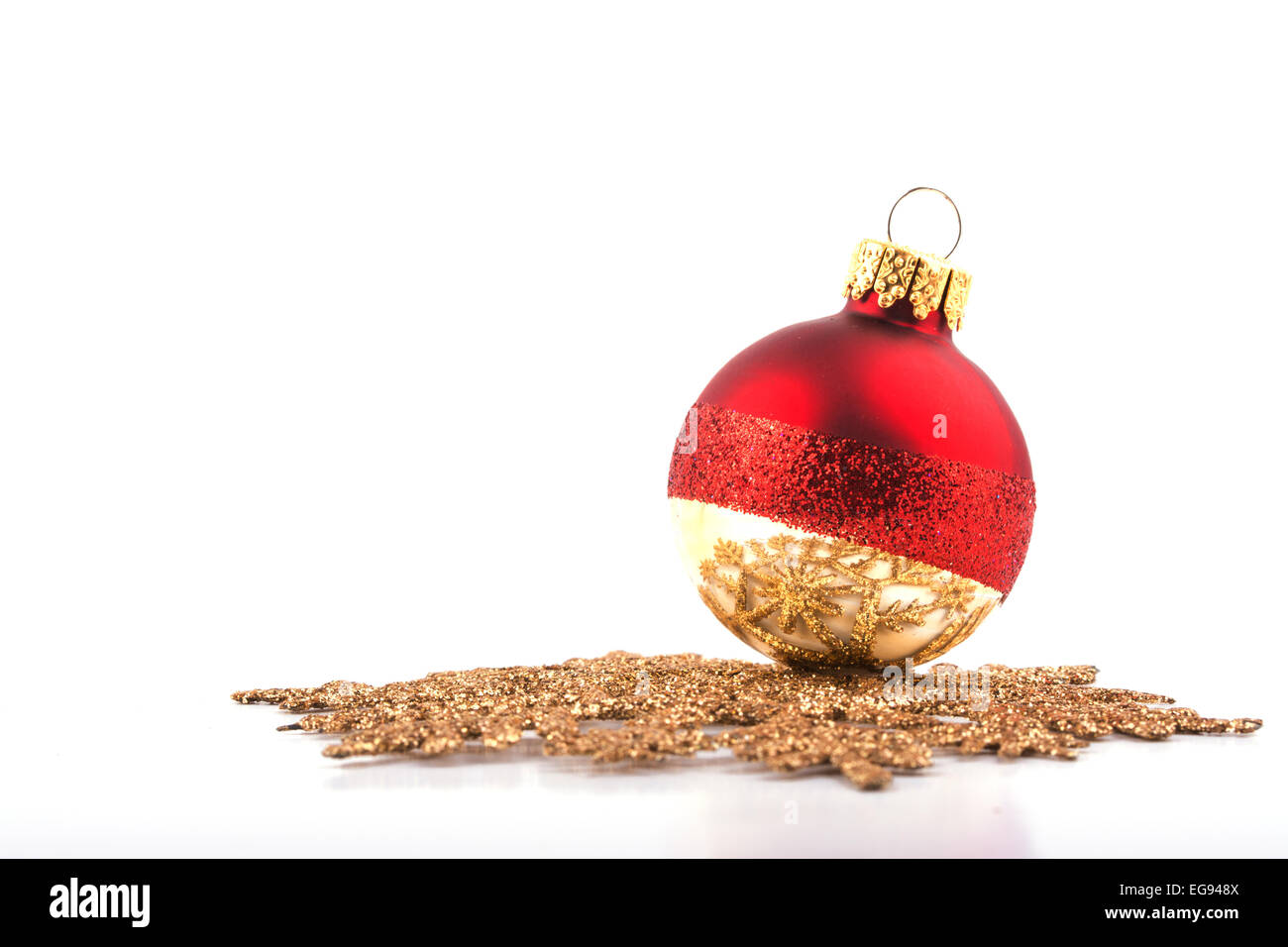 Boule de Noël reposant sur un flocon d'or, l'accent sur la réflexion sur la bauble ; on white Banque D'Images