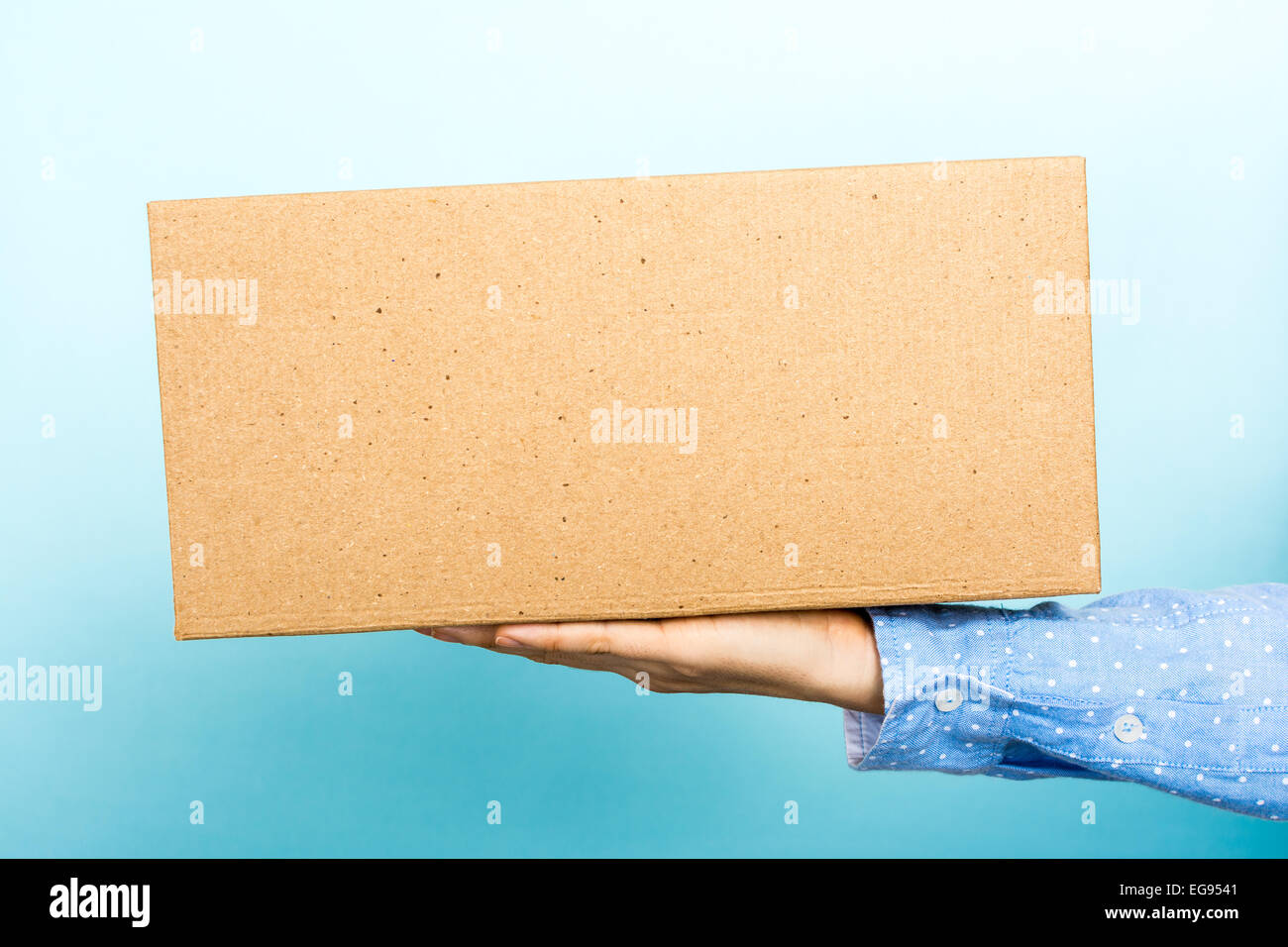 Femme pesant une boîte en carton avec sa main. Utile pour l'annonce, les informations d'expédition, ainsi de suite. Banque D'Images