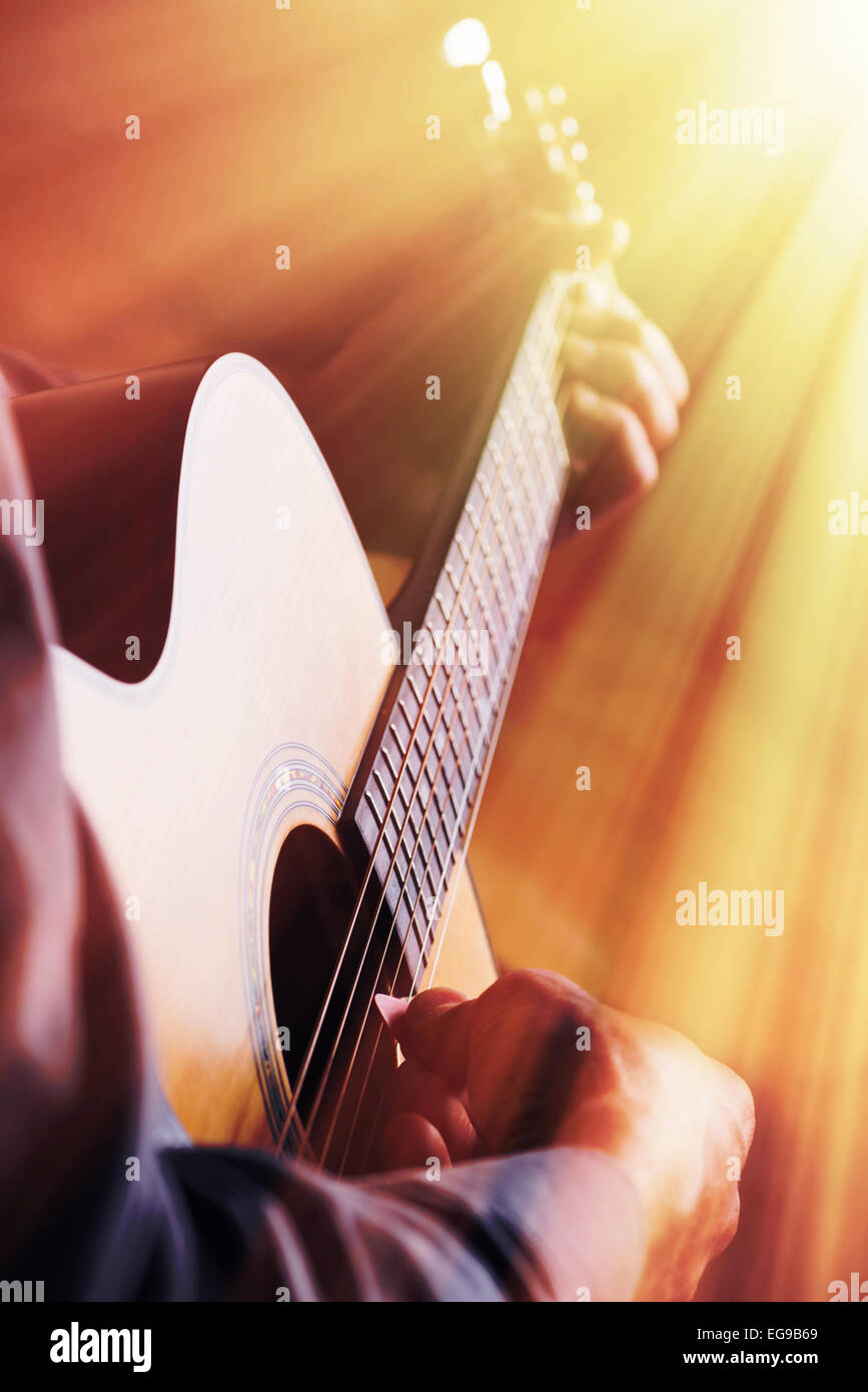 Le guitariste joue sur guitare acoustique en face de la lumière Banque D'Images