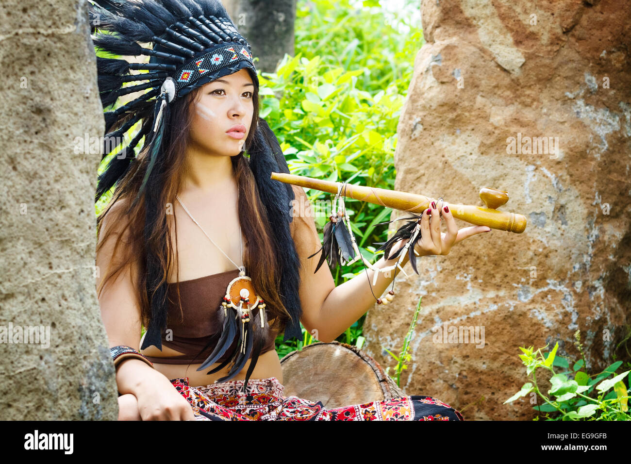 Amérindiens, indiens, en costume traditionnel assis dans un bosquet de pierre avec un tuyau Banque D'Images