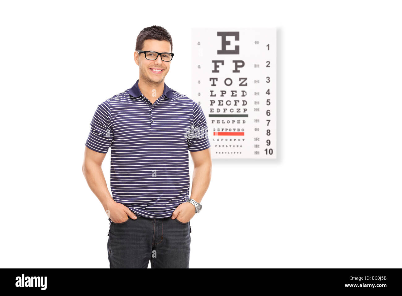 Jeune homme avec des lunettes, debout devant un test de la vue isolé sur fond blanc Banque D'Images